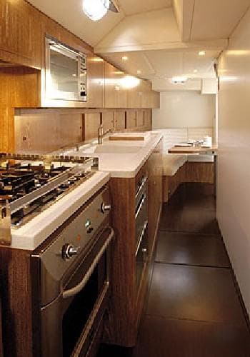 Modern yacht kitchen with wood cabinetry, stainless steel appliances, and sleek countertops, CNB 104 model.