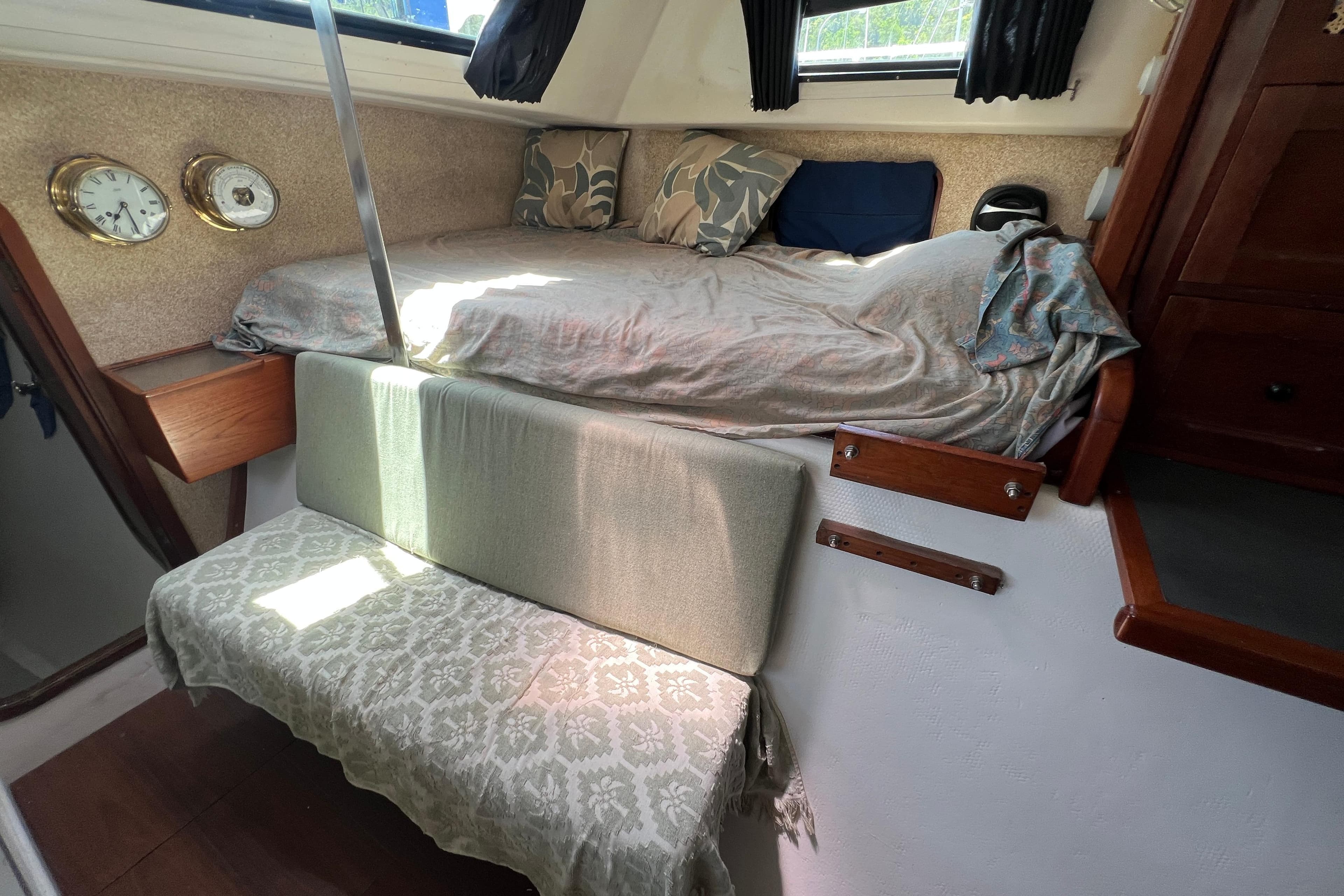 Cozy interior of 1989 Beuhler Custom Trimaran with bed, seating, and nautical decor.