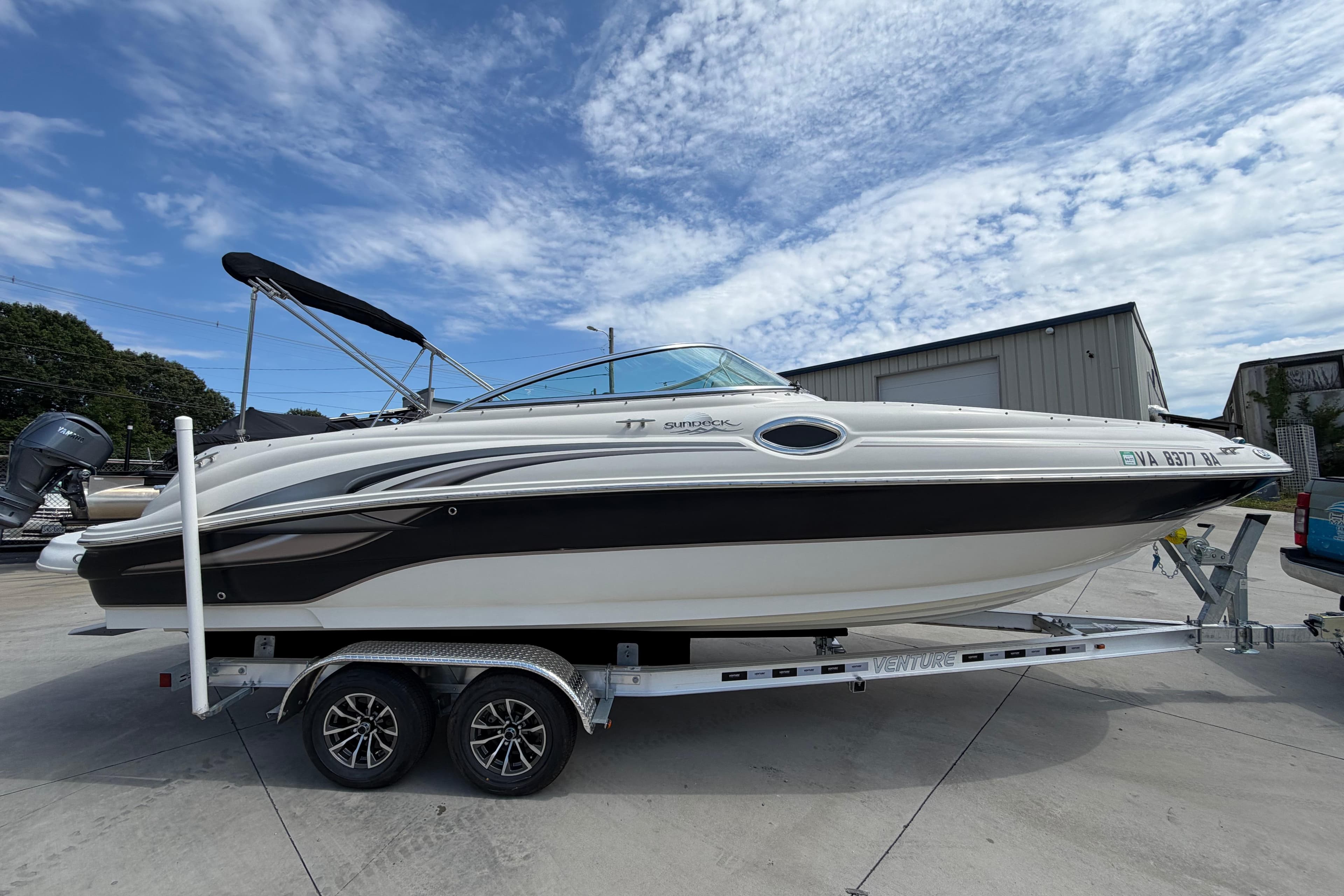 2003 Sea Ray 240 Sundeck boat on trailer under a partly cloudy sky.