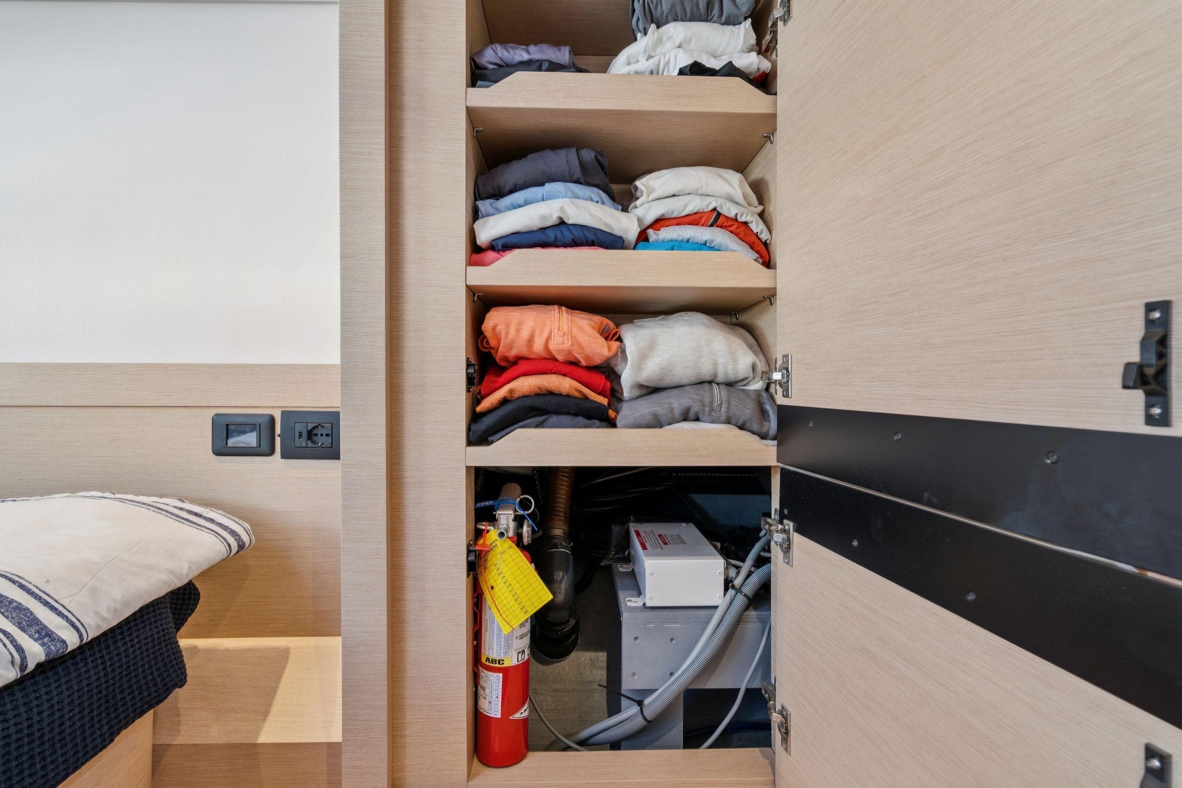 Cabin storage on 2019 Itacatamarans 14.99 with clothes and fire extinguisher.