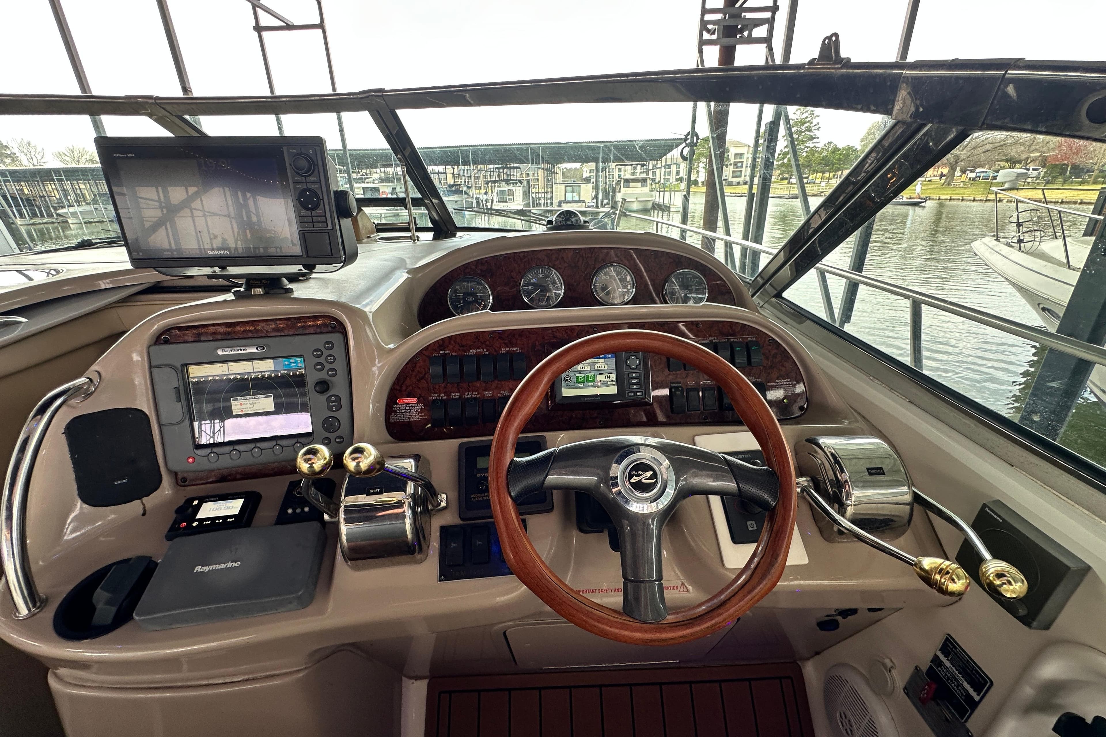 2005 Sea Ray 360 Sundancer helm with navigation equipment and wooden steering wheel.