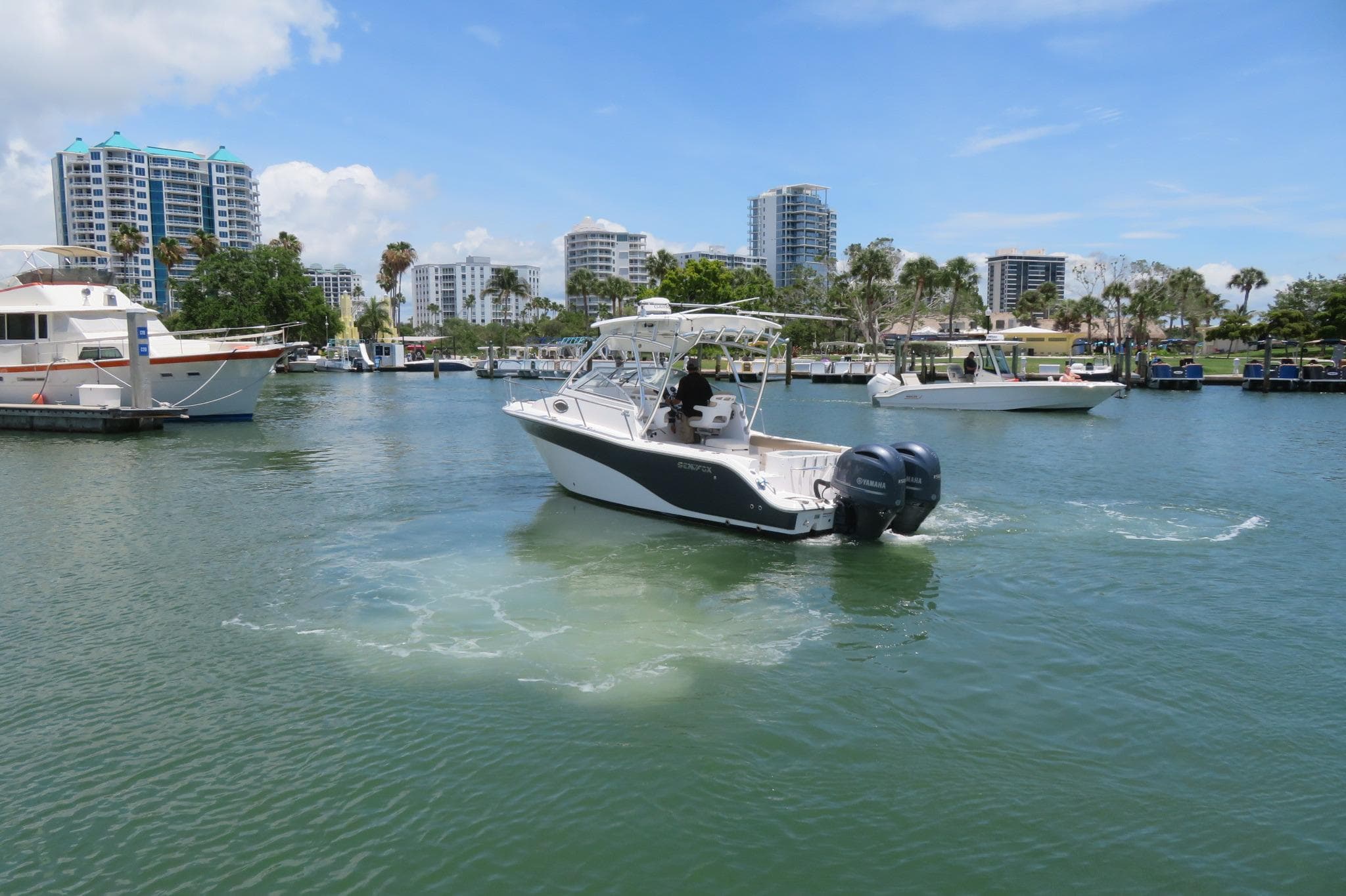 2017 Sea Fox 256 Voyager cruising in a marina with modern buildings in the background.
