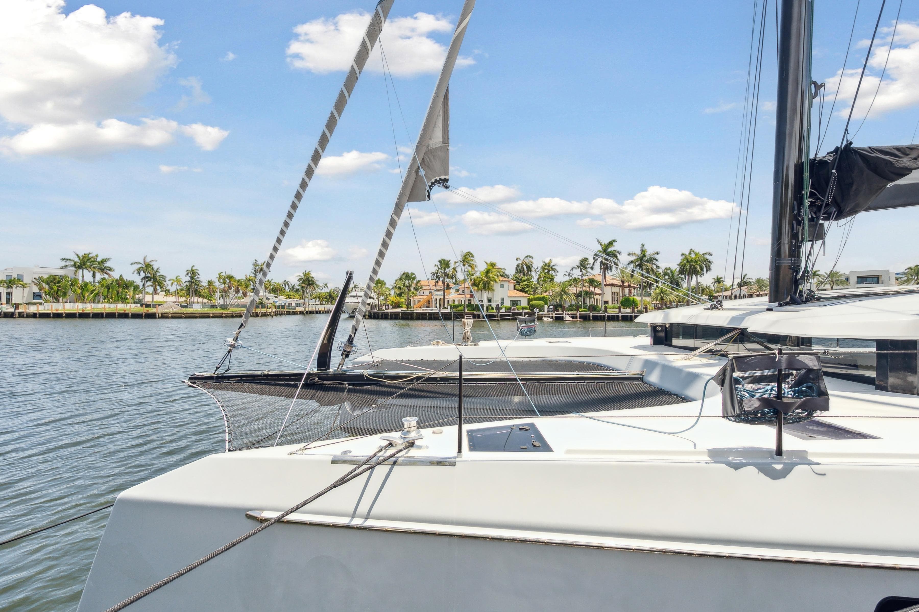 2019 McConaghy MC60 yacht on calm water, with palm trees and houses in the background.