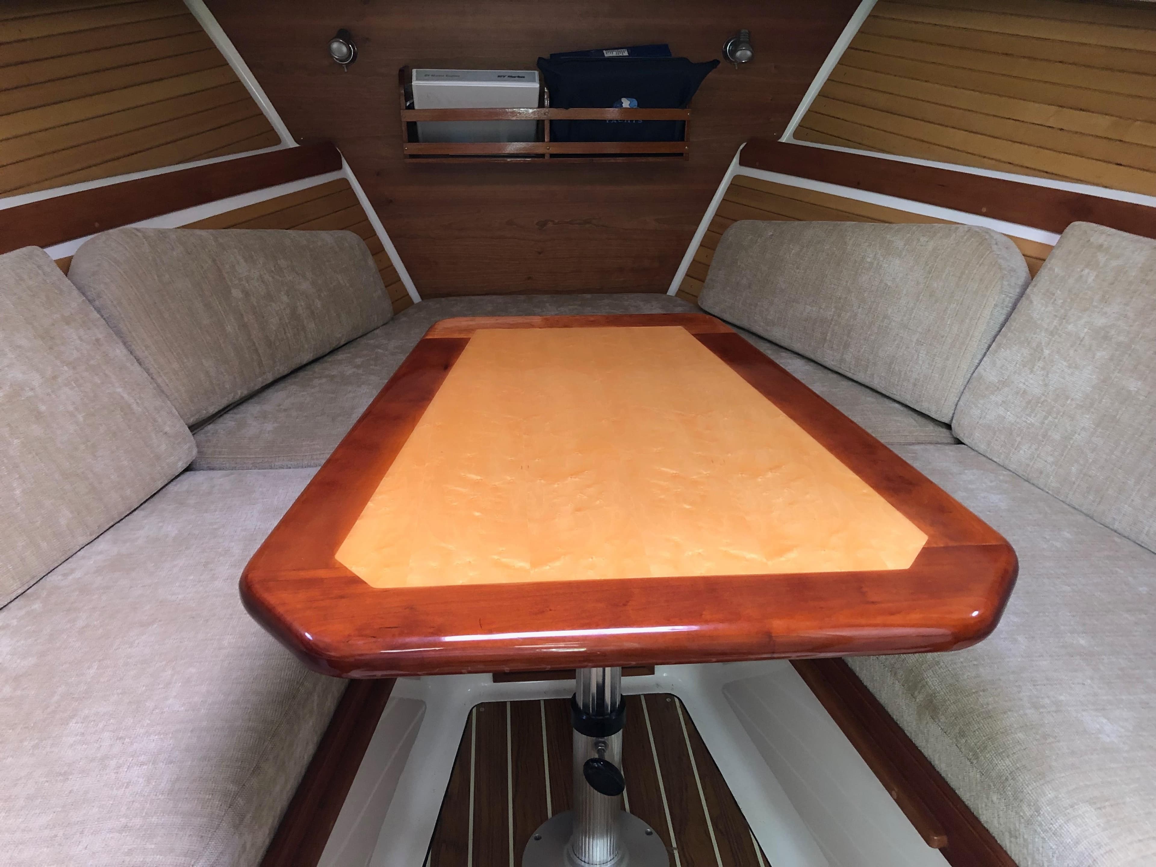 Interior of 2008 Back Cove 29 boat with wooden table and cushioned seating.