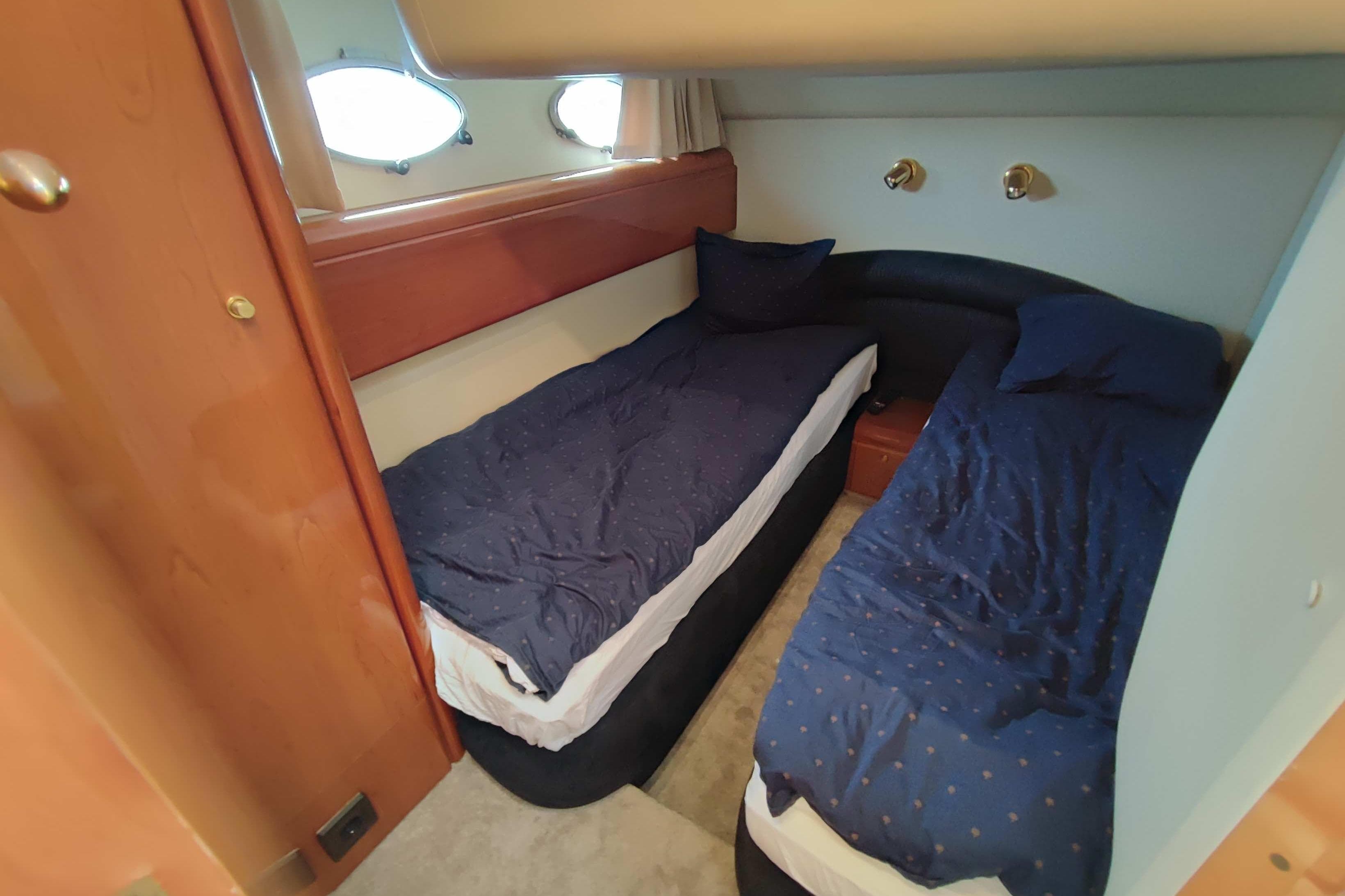 Twin cabin with blue bedding in 1998 Princess V55 yacht interior.