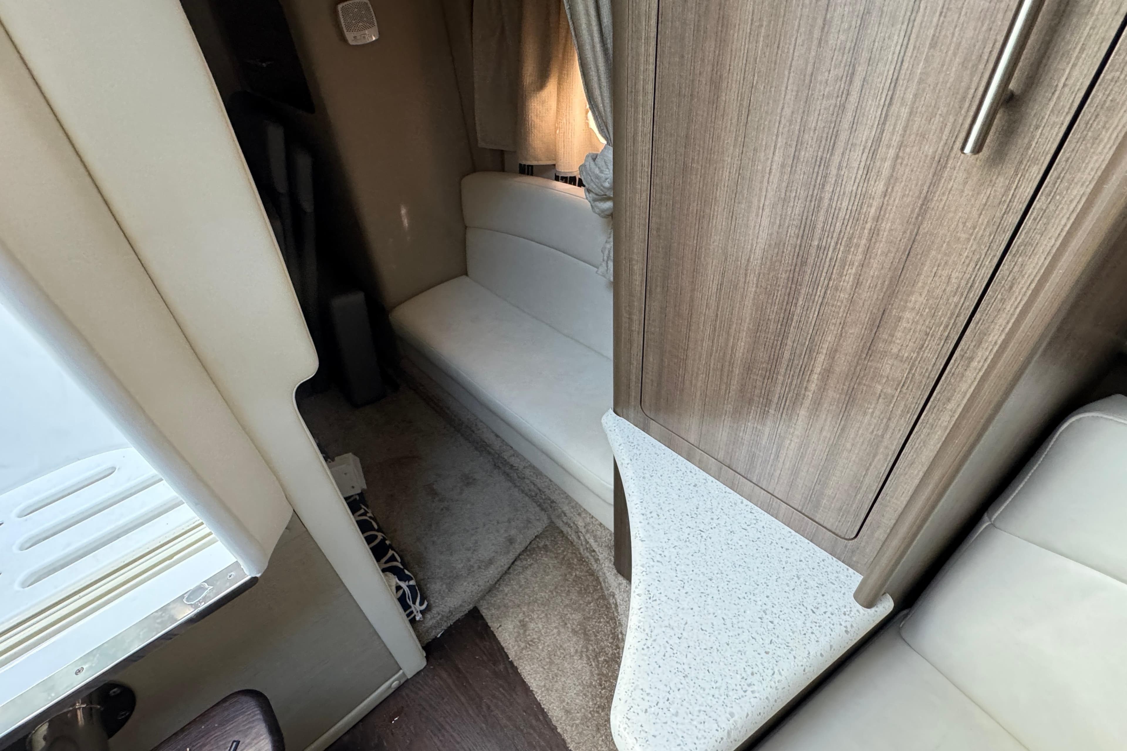 Interior of a 2020 Rinker 320 EX boat, featuring seating and wood cabinetry.