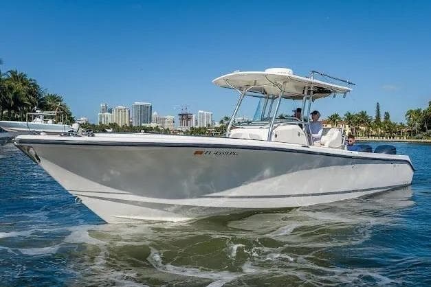 2010 Edgewater 318CC boat cruising on a sunny day near a city skyline.