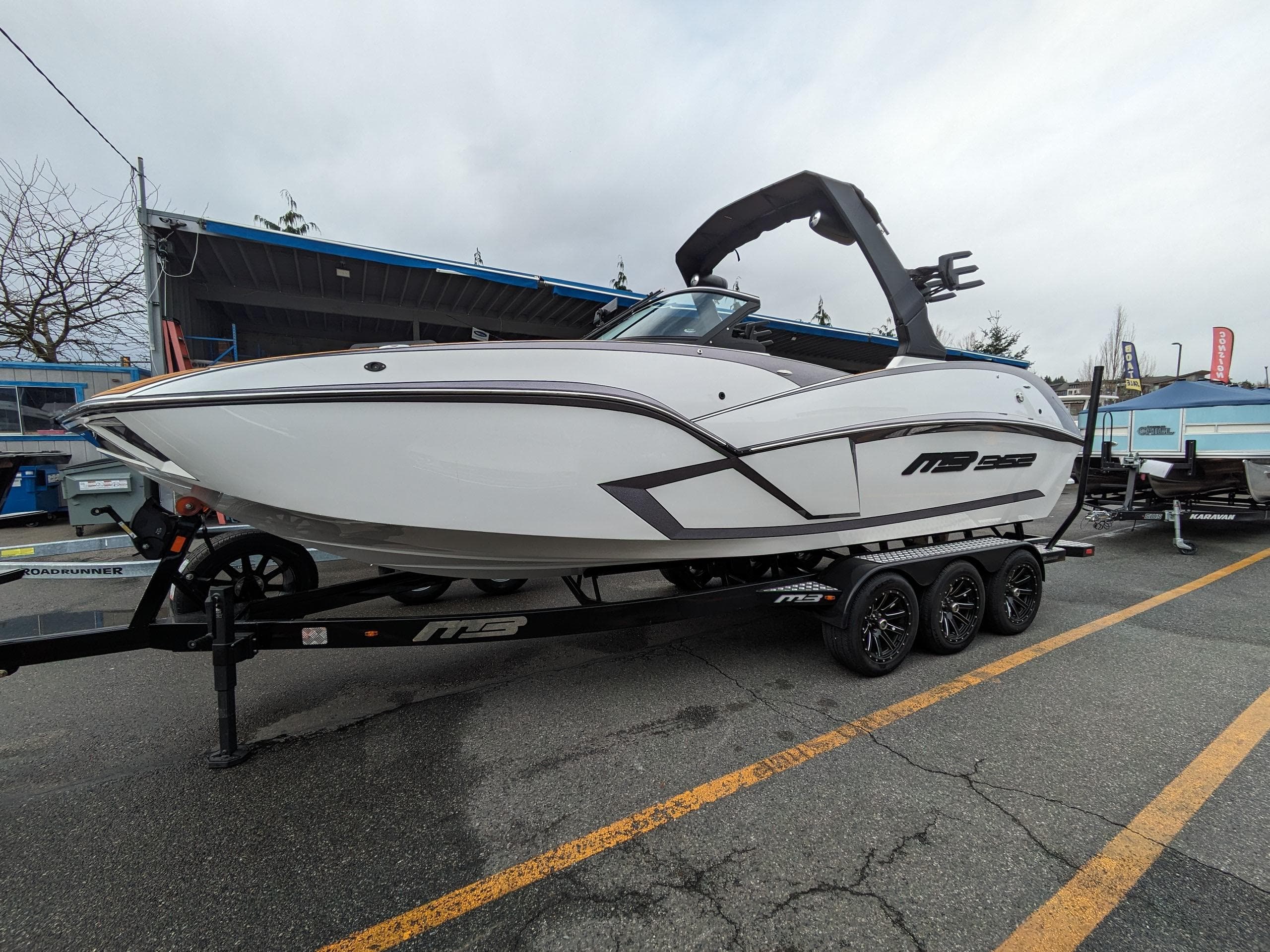 2025 MB B52 25 Alpha boat on trailer, sleek design, parked outdoors.