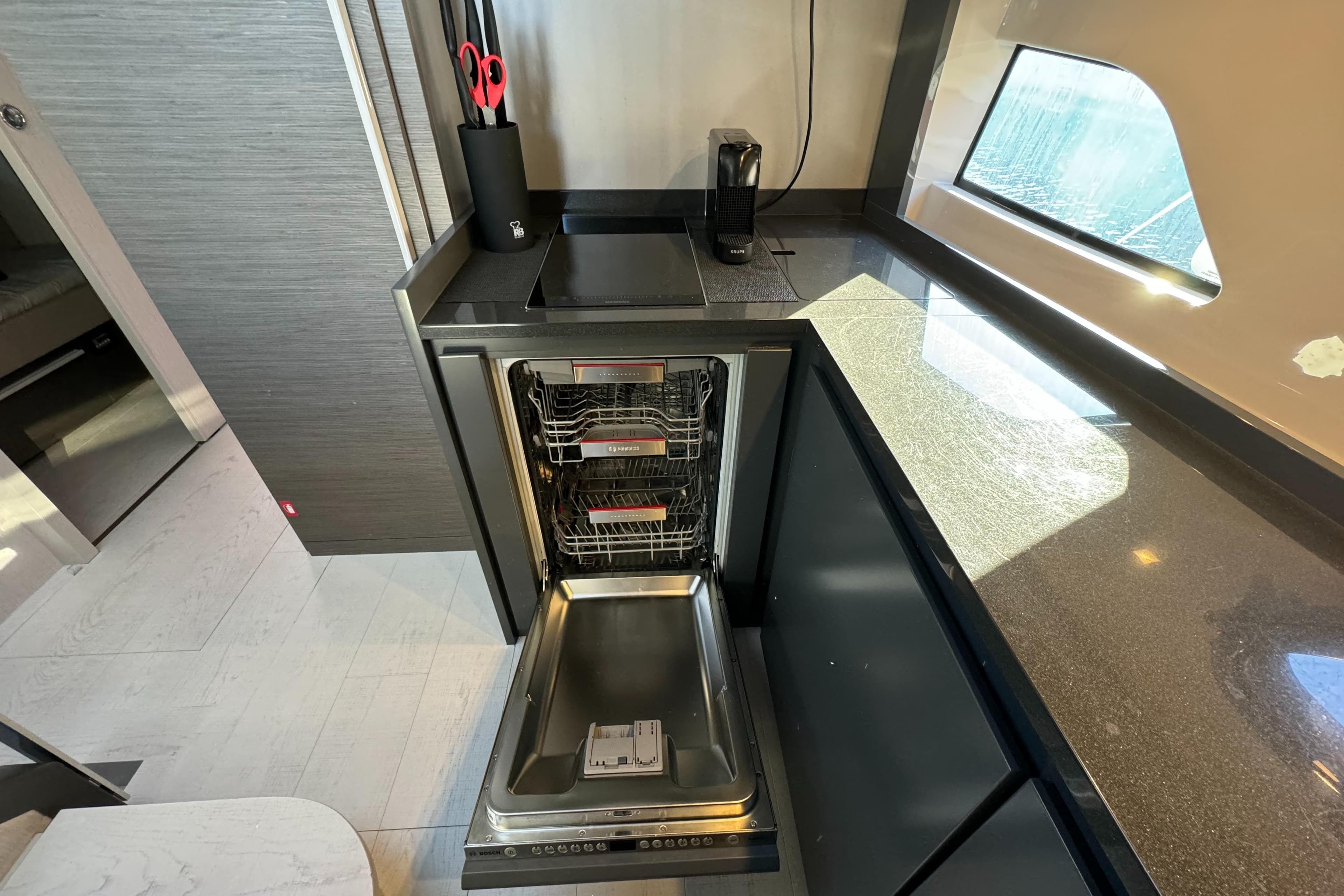 Modern kitchen in 2021 Pershing 5x yacht with open dishwasher and sleek countertops.