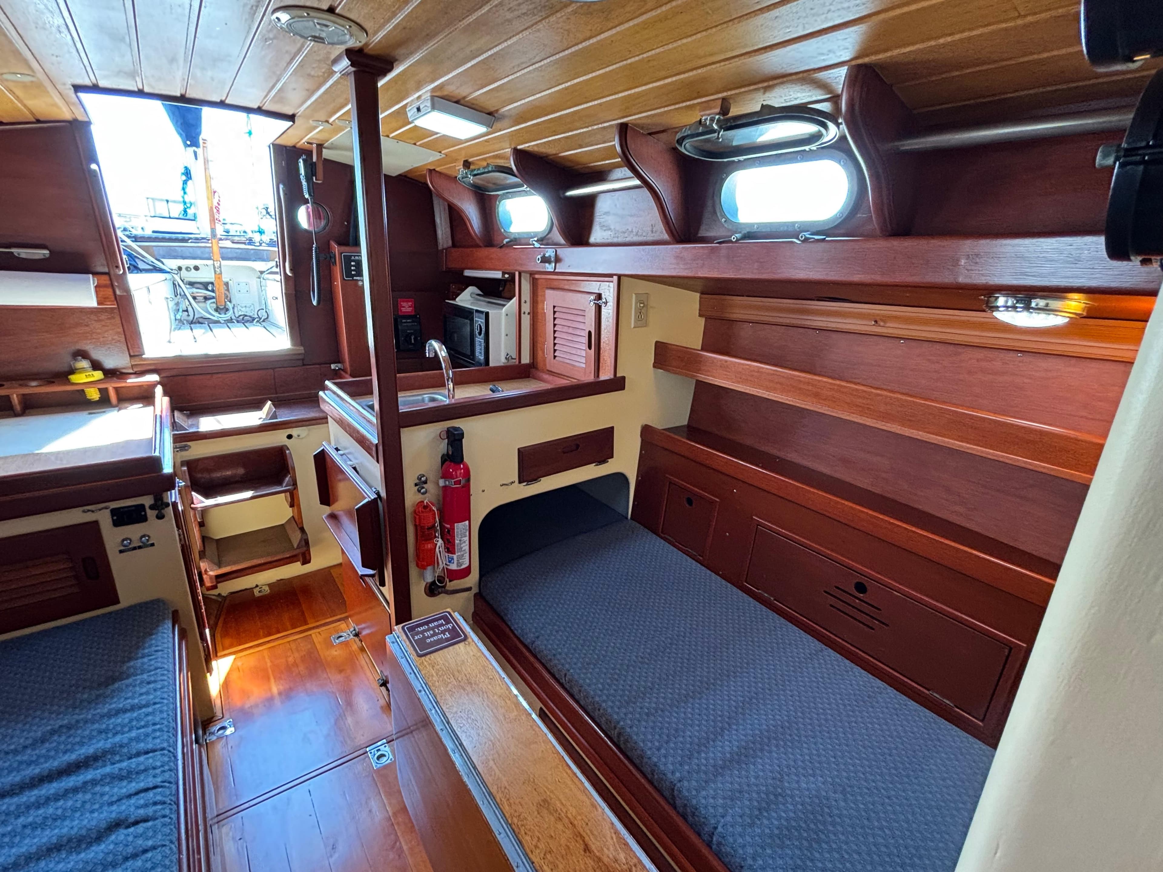 1955 Hinckley 36 Auxiliary Yawl interior with wooden finish and cozy sleeping area.