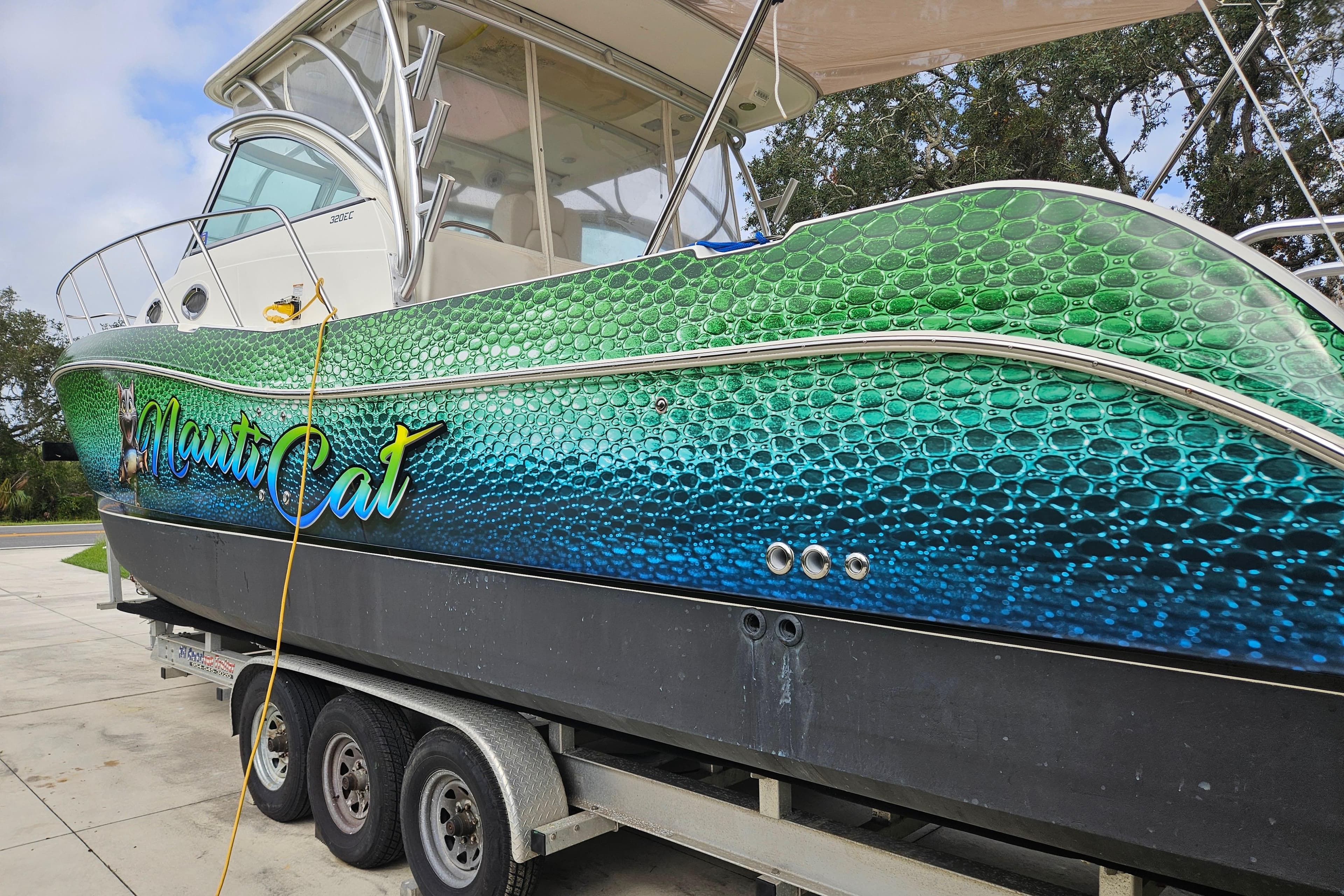 2014 World Cat 320 EC boat with vibrant green and blue scale design on trailer.