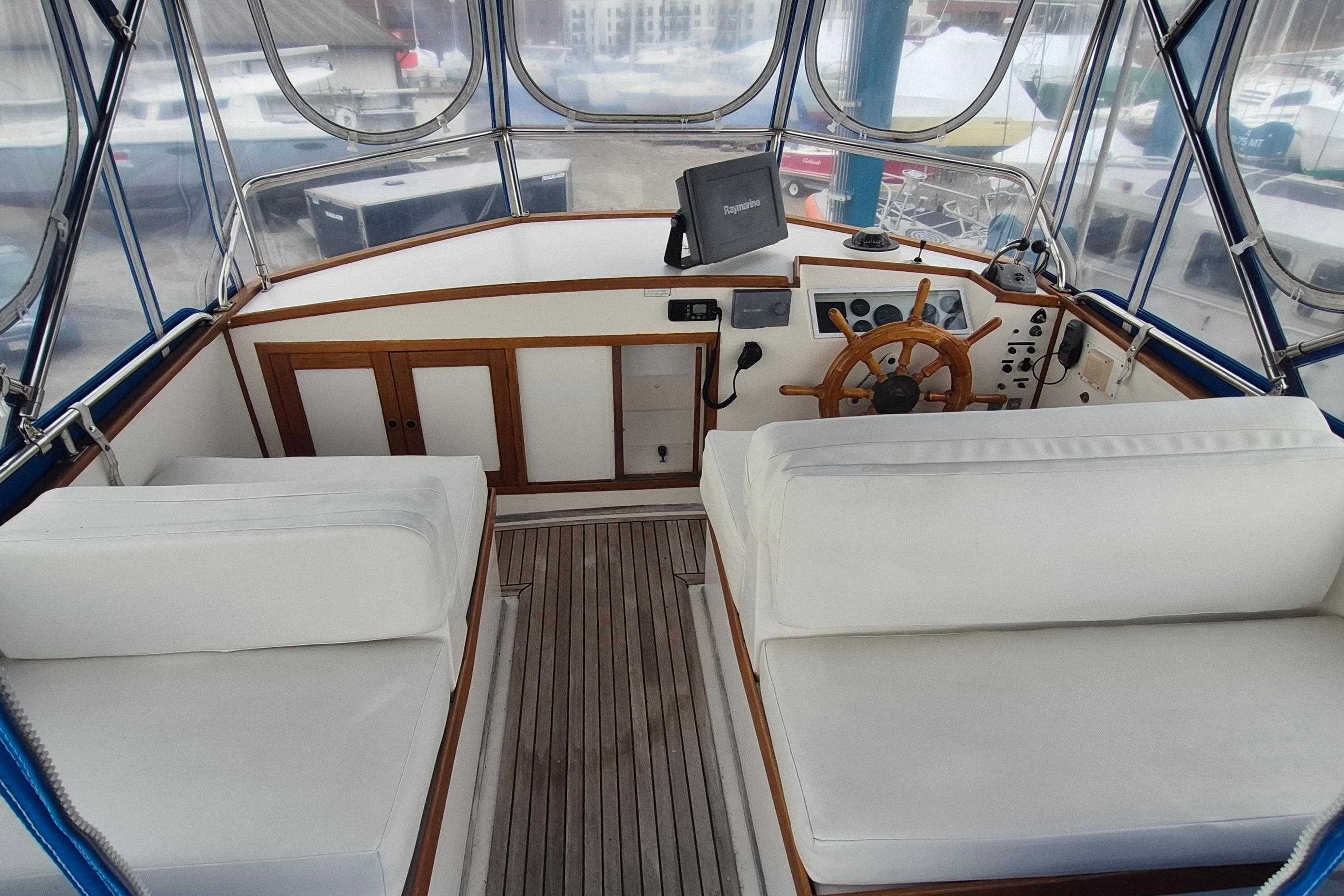 1983 Grand Banks 42 Classic yacht helm with wooden wheel and white seating.