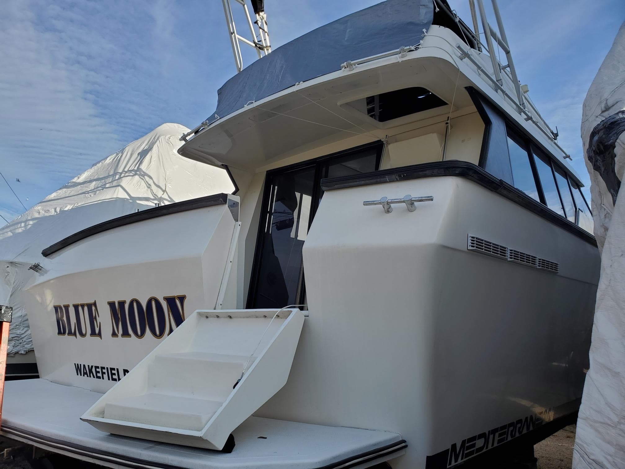 1990 Mainship Mediterranean yacht "Blue Moon" docked, featuring sleek design and open rear deck.