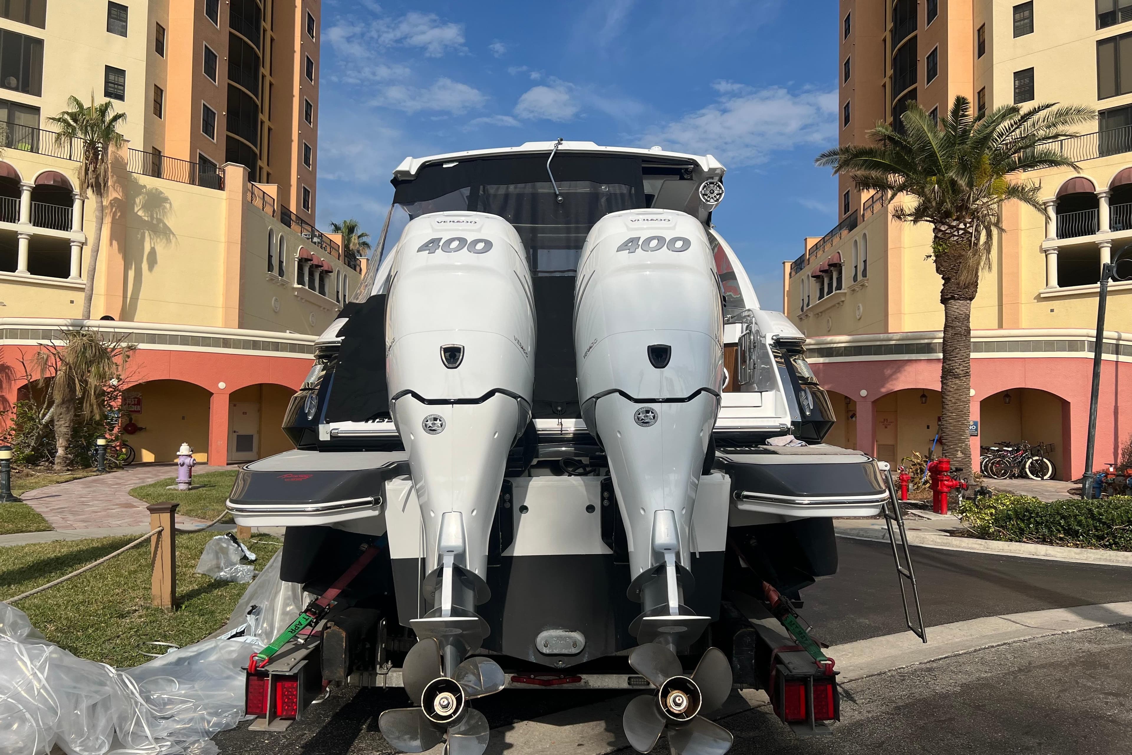 2023 Four Winns H350 OB boat with dual 400 horsepower engines, parked near colorful buildings.