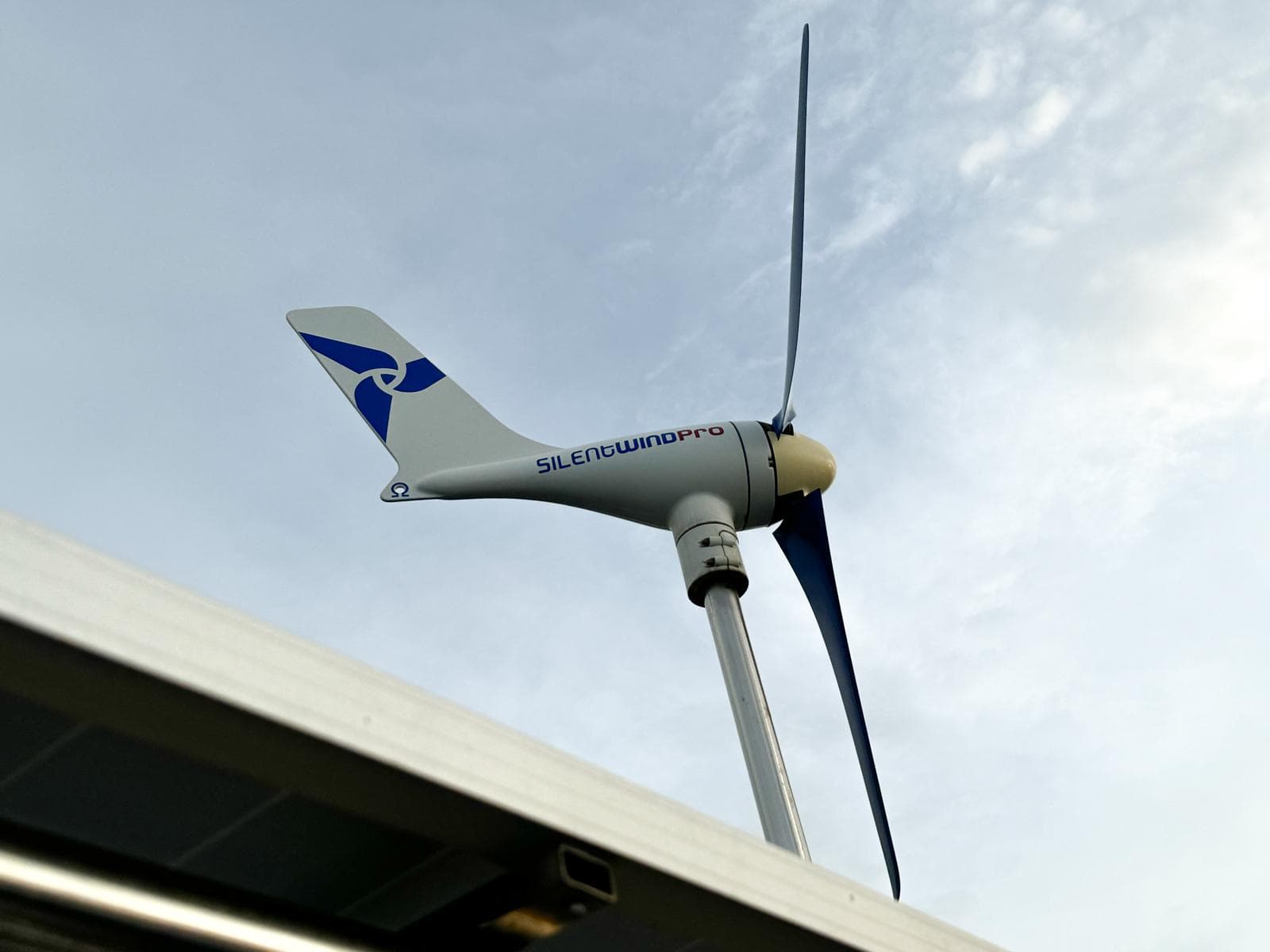 Wind turbine on a 2006 Beneteau Oceanis 473 sailboat against a cloudy sky.