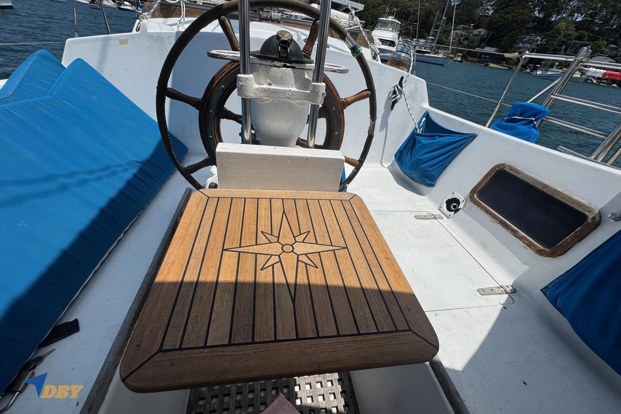 Cockpit of 1987 Bowman 47 sailboat with wooden table and steering wheel.