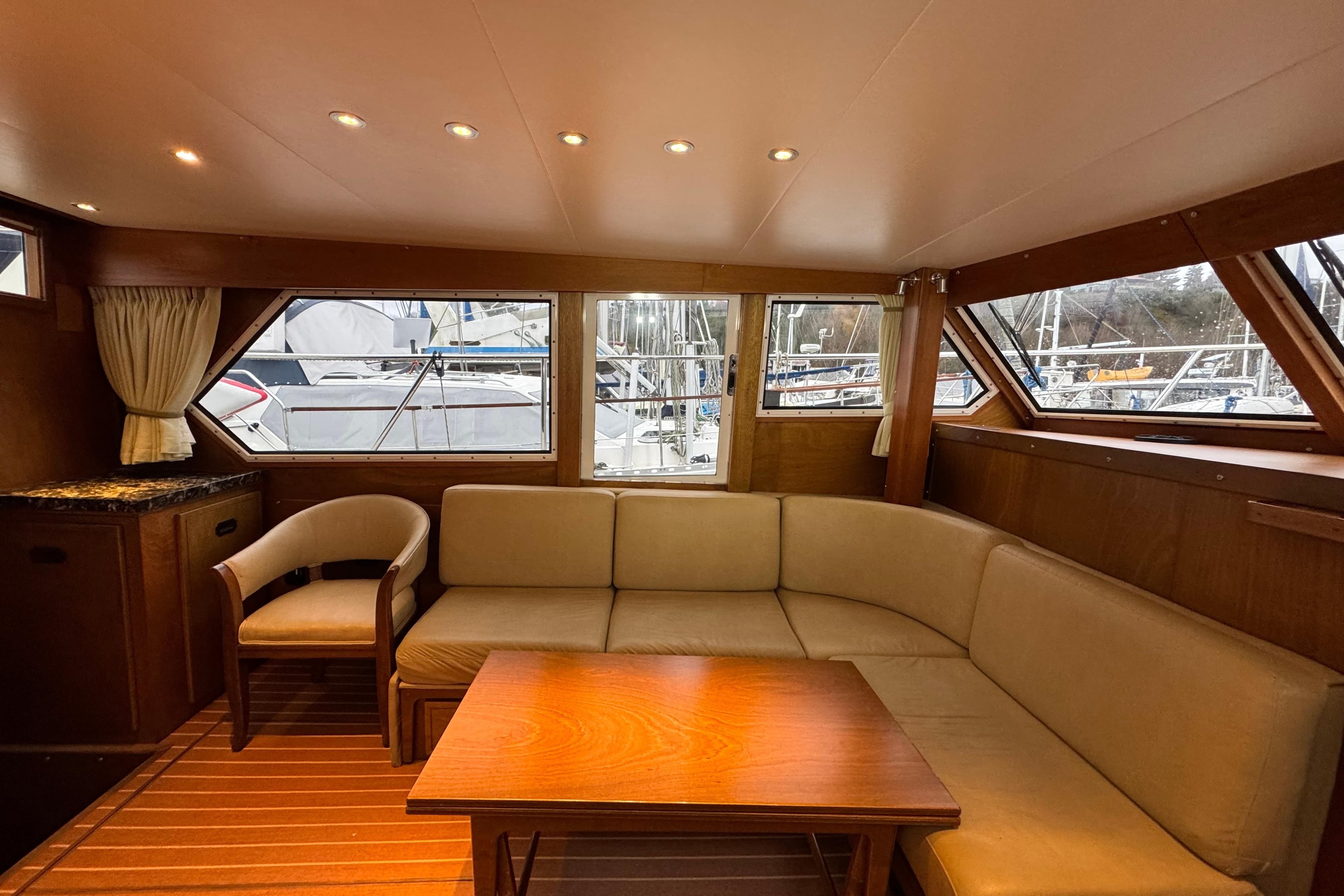 Cozy interior of 1974 Tollycraft 40 Tri-Cabin MY with beige seating and wooden accents.