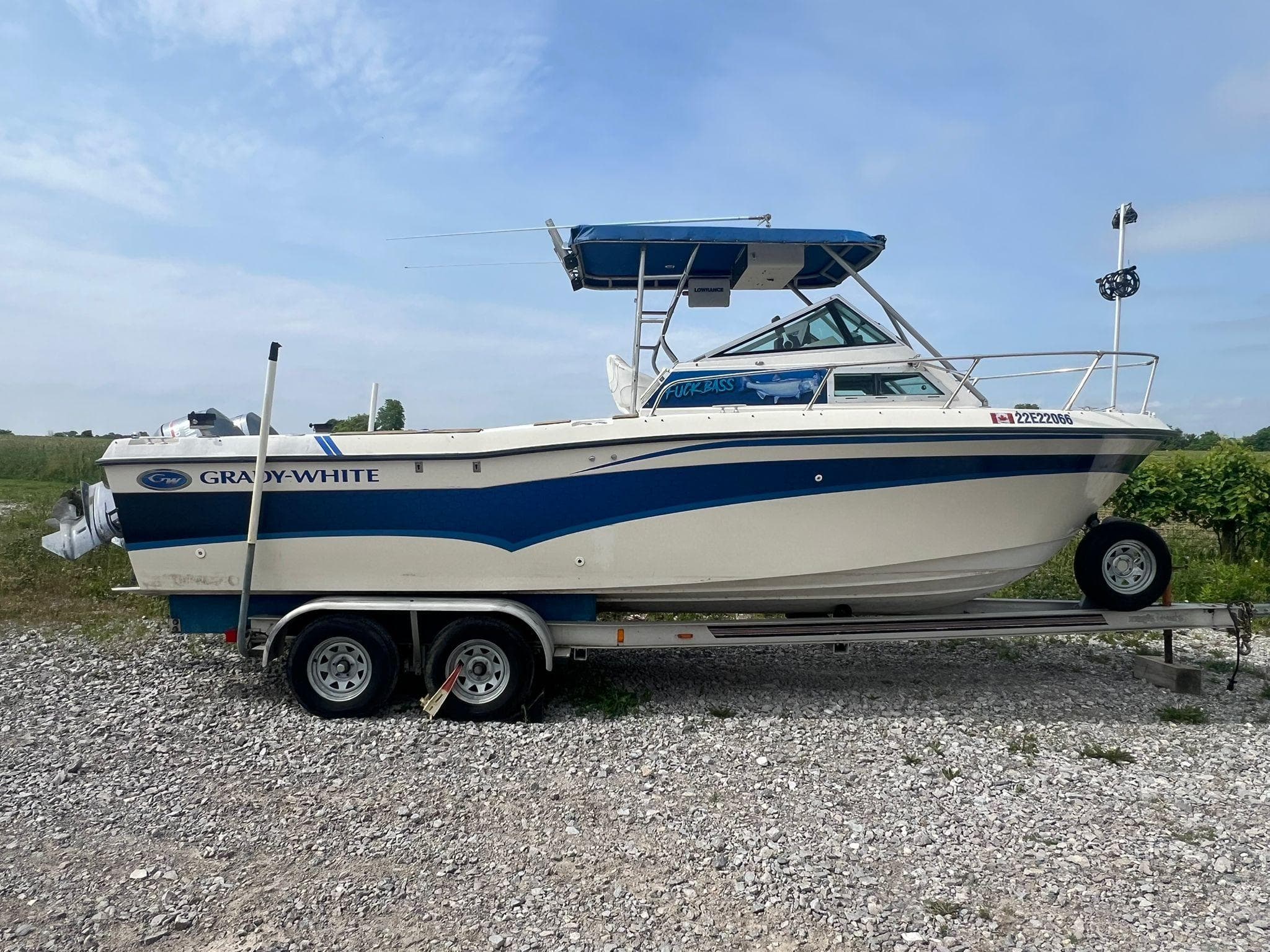 1988 Grady-White Offshore 240 boat on trailer, parked on gravel, with blue and white design.