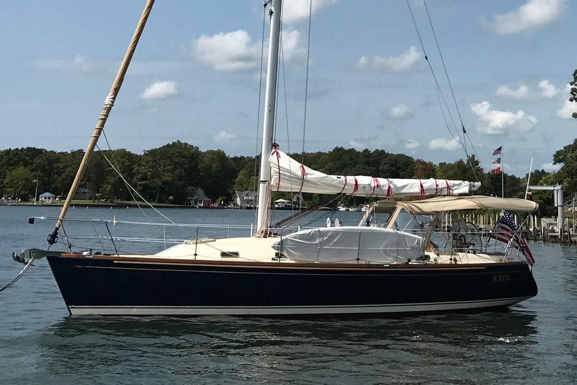 2007 Sabre 386 sailboat on calm water with trees in the background.