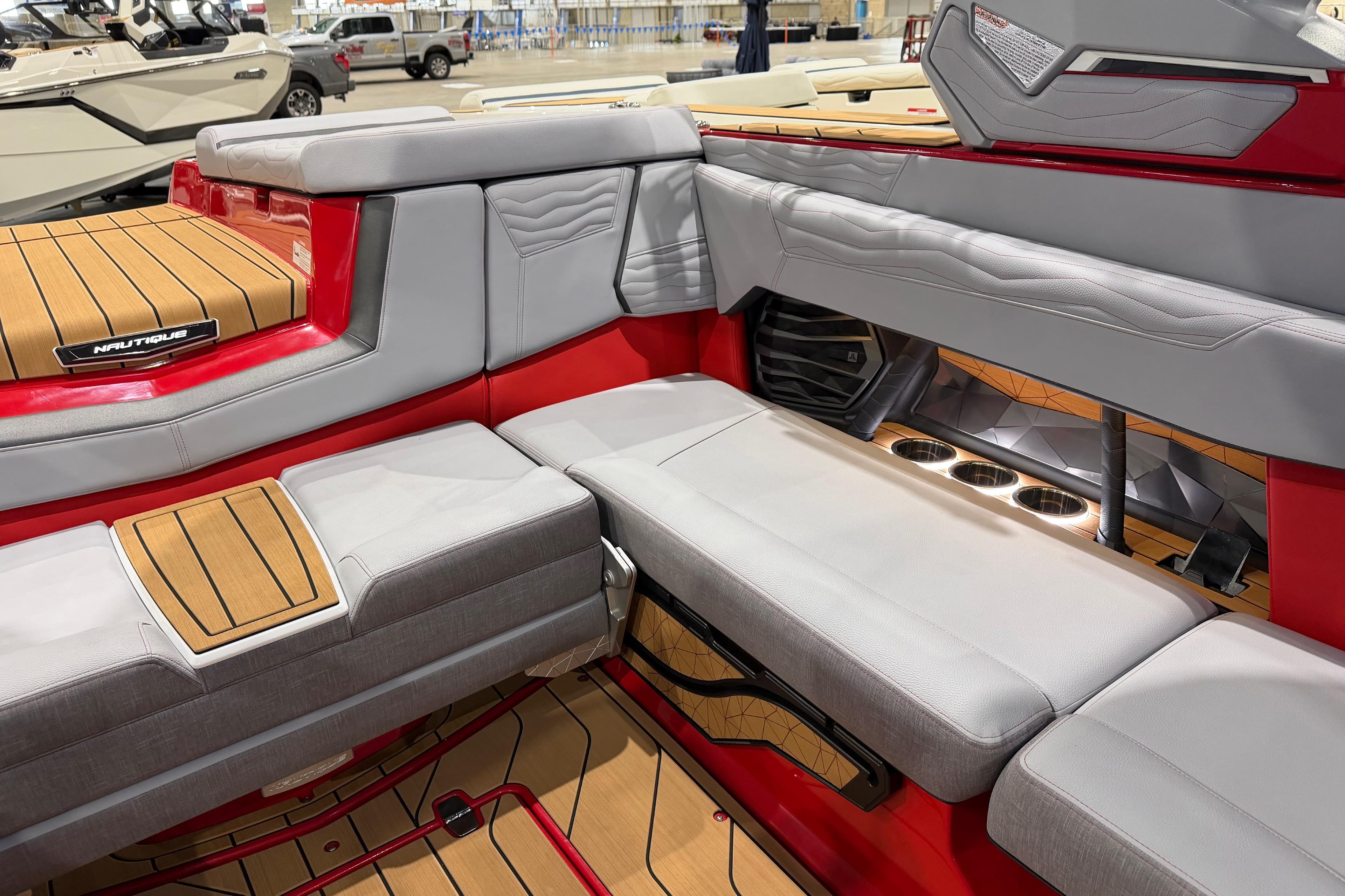 2026 Nautique Super Air Nautique G23 interior with red and gray seating, cup holders, and teak flooring.