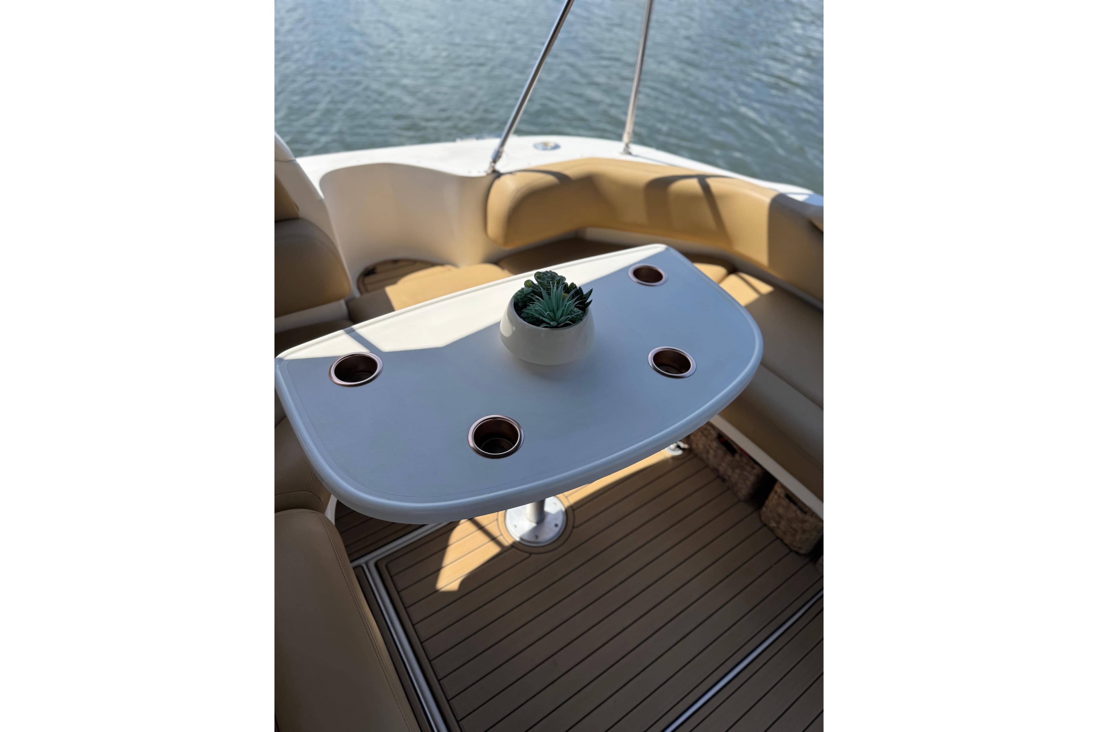 Cockpit seating area on a 2002 Sea Ray 380 Sundancer with a table and potted plant.