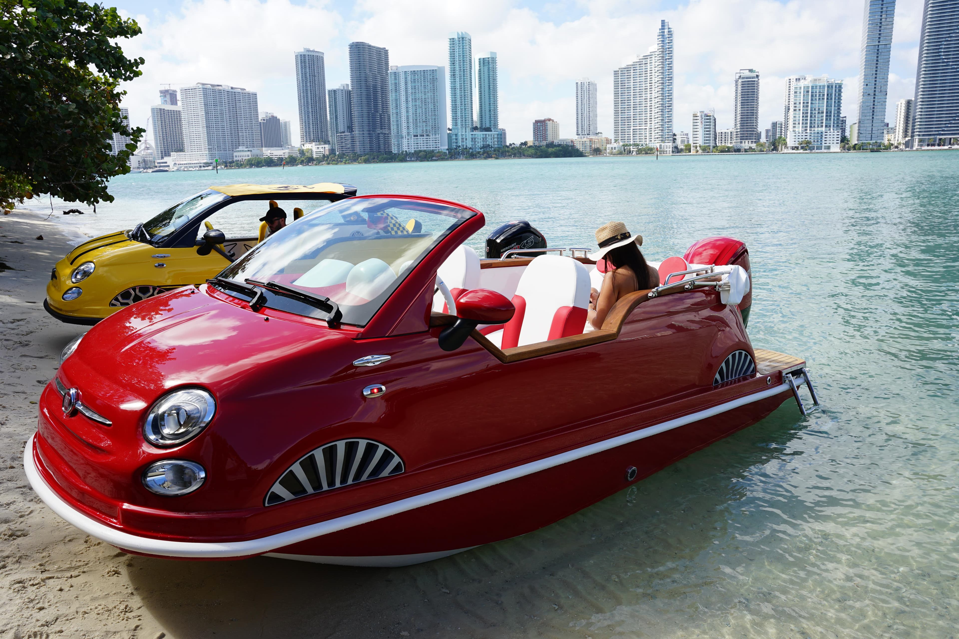 Red Fiat 500 Classic boat on water, city skyline in background, 2025 model.