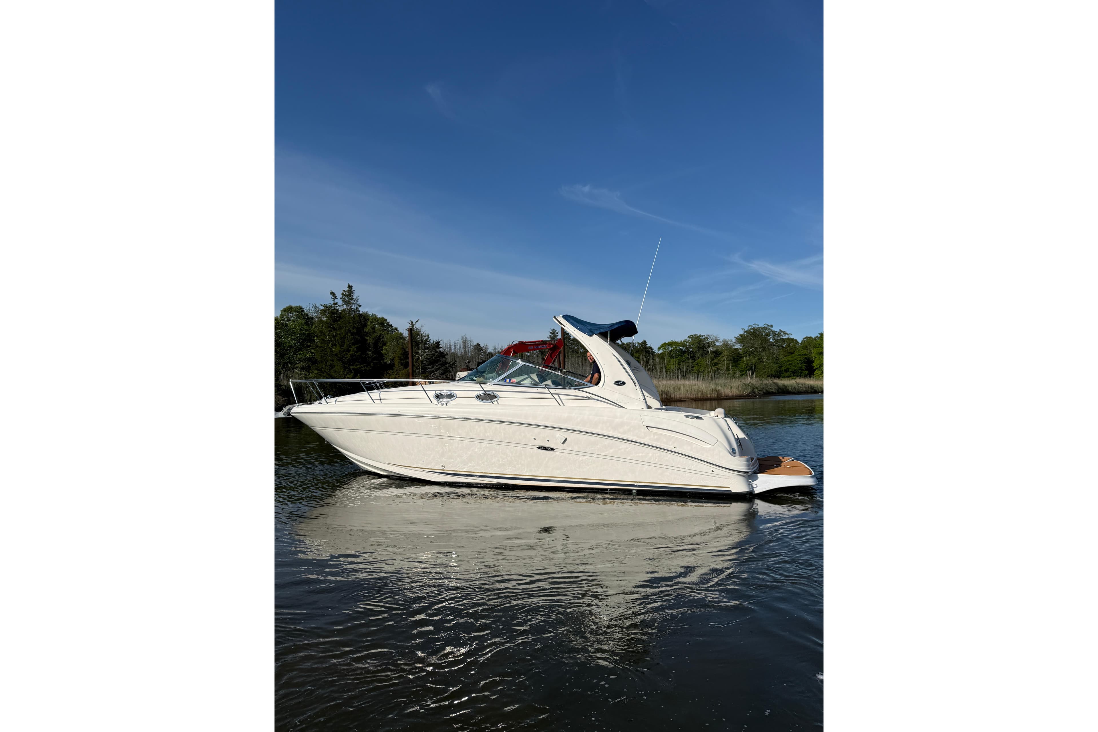 2002 Sea Ray 300 Sundancer boat on calm water under clear blue sky.