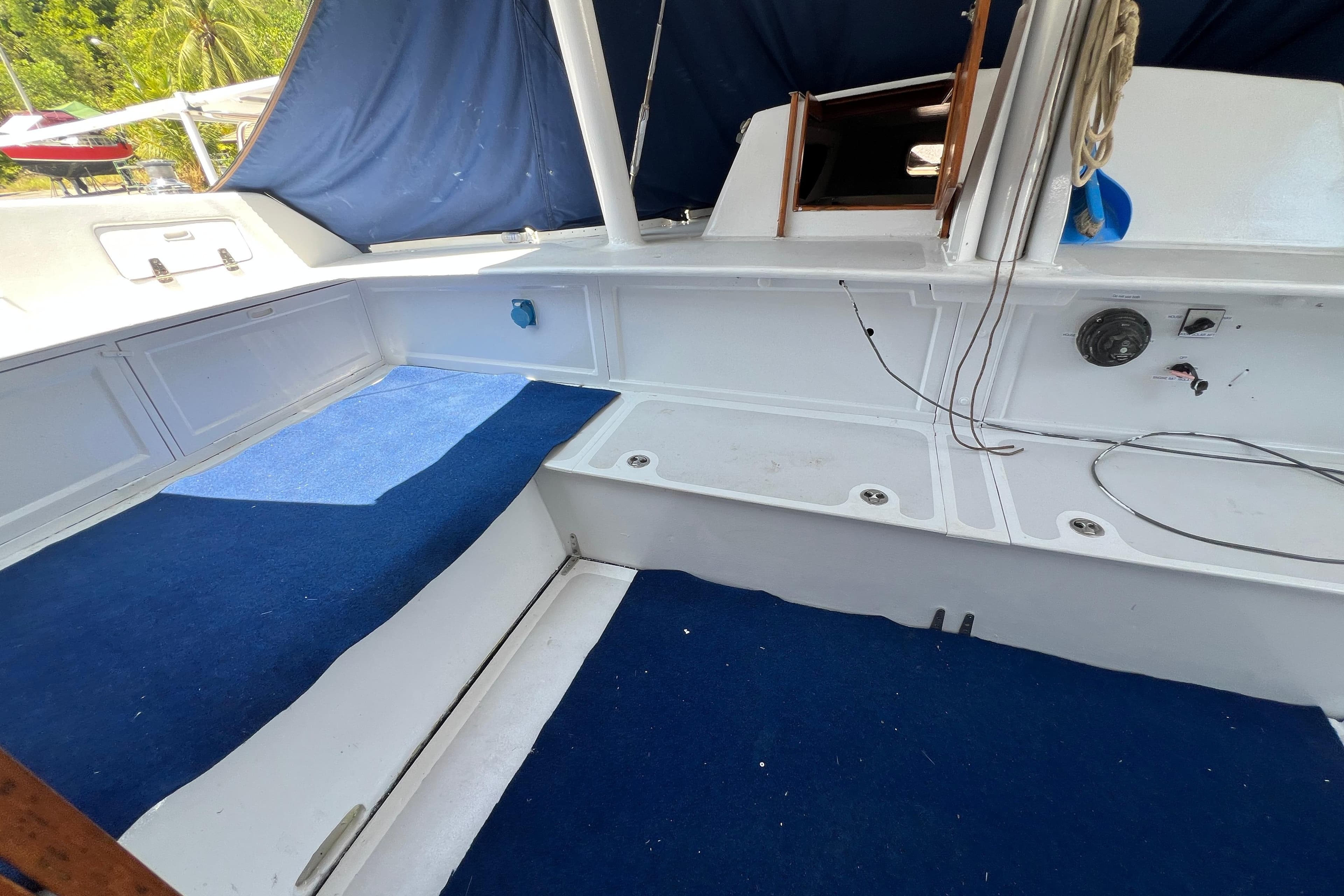 1989 Beuhler Custom Trimaran interior with blue carpet and white seating area.