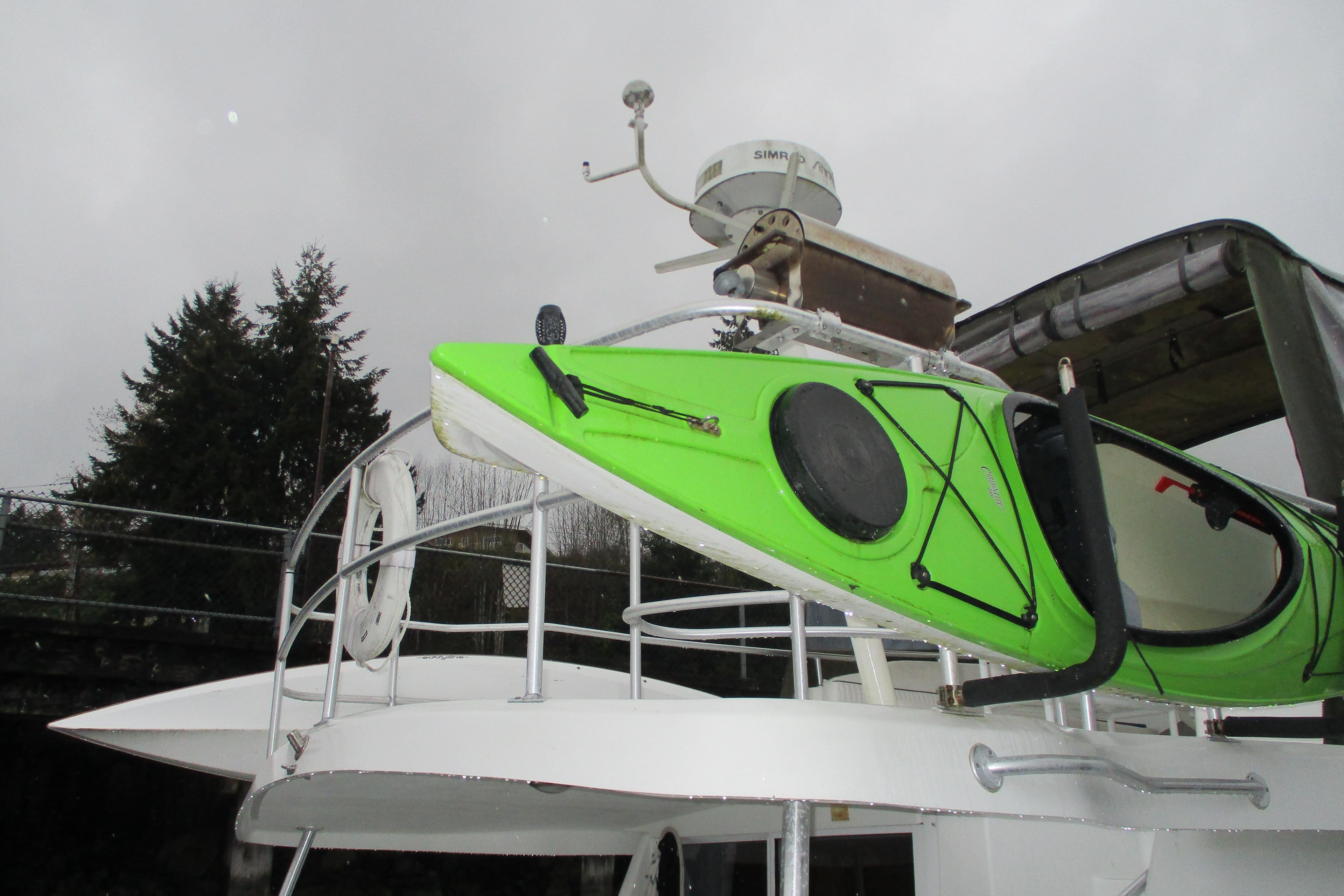 Green kayak on 1997 Mainship 350 Trawler deck, overcast sky background.