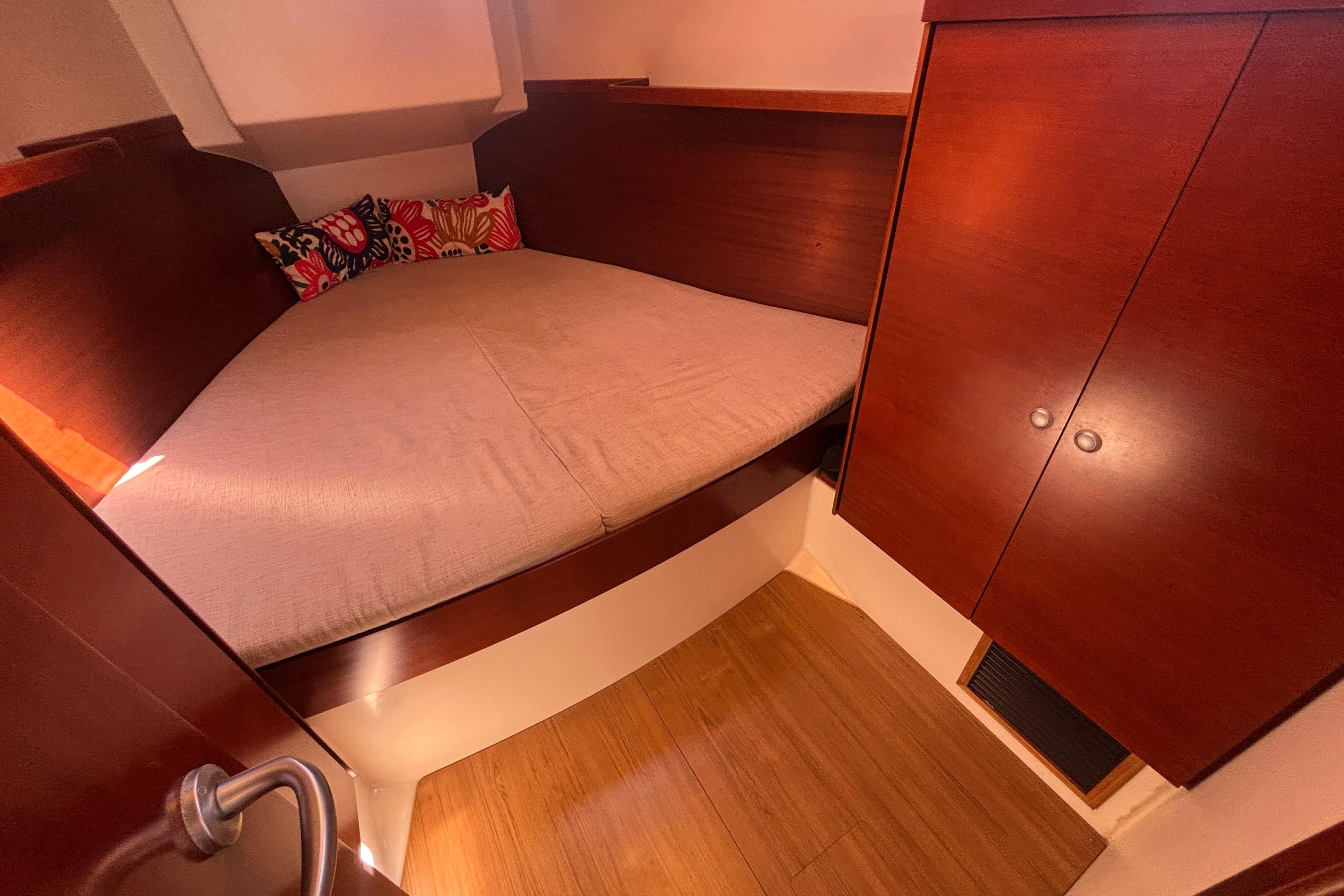 Cozy cabin interior of 2008 Hanse 370 yacht with wooden finish and colorful cushions.