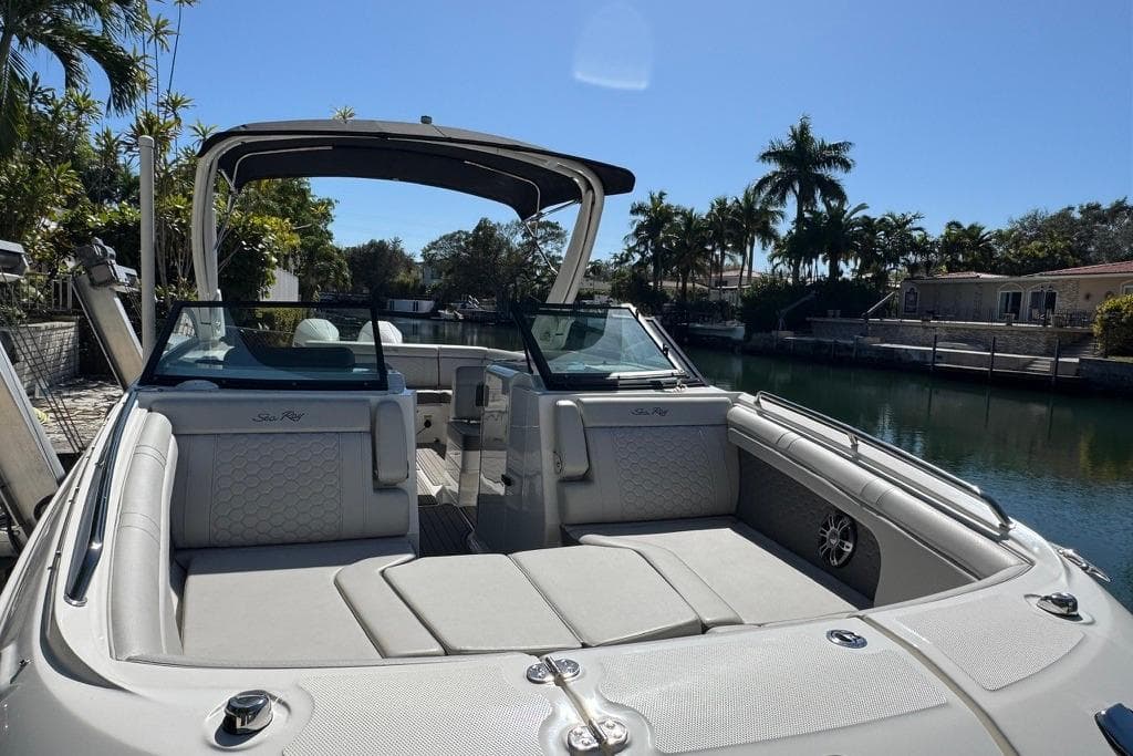 2025 Sea Ray SDX 290 Outboard boat with luxurious seating, docked by a scenic canal.