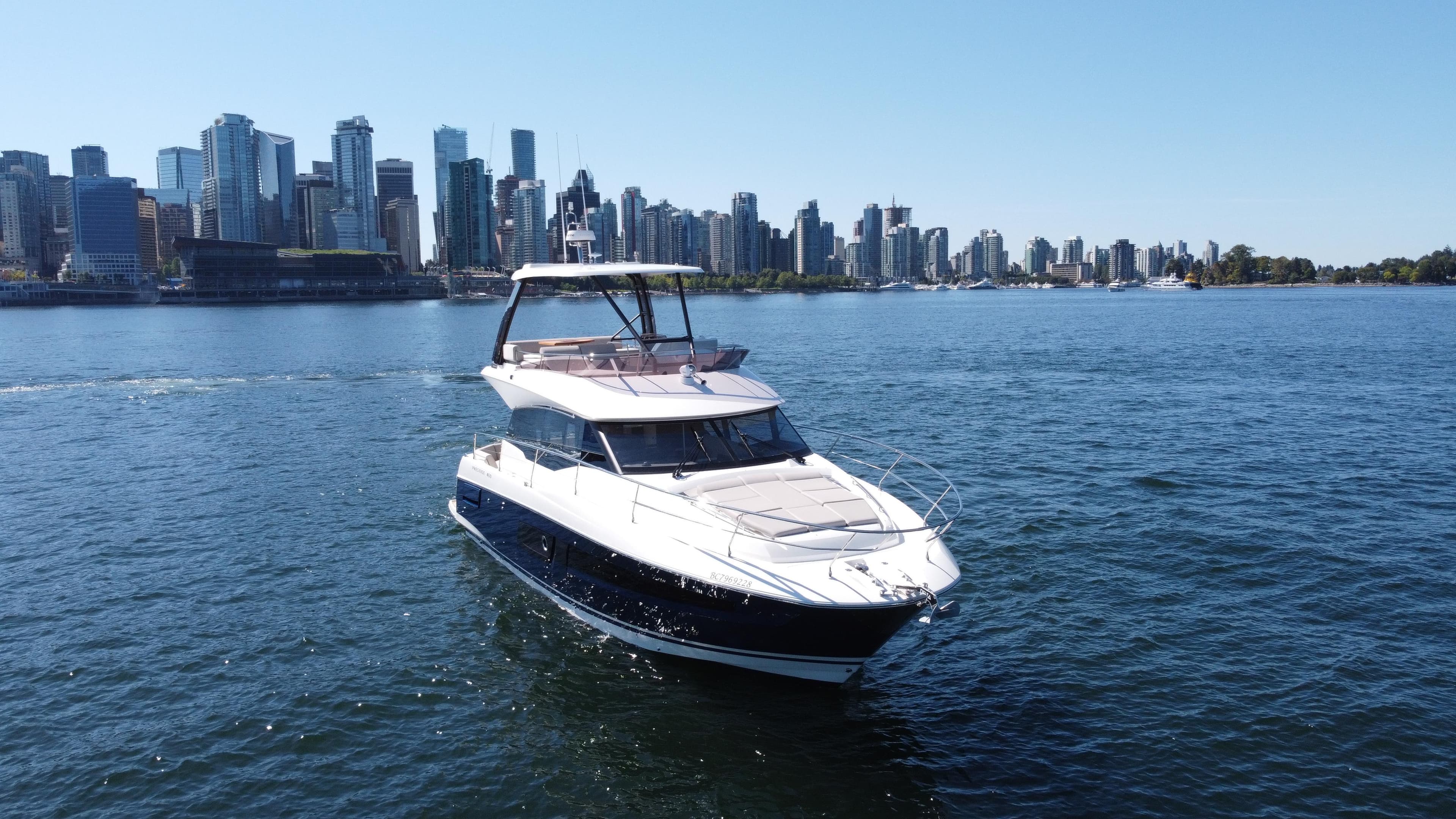 Luxury 2022 Prestige 460 yacht cruising near city skyline on a sunny day.