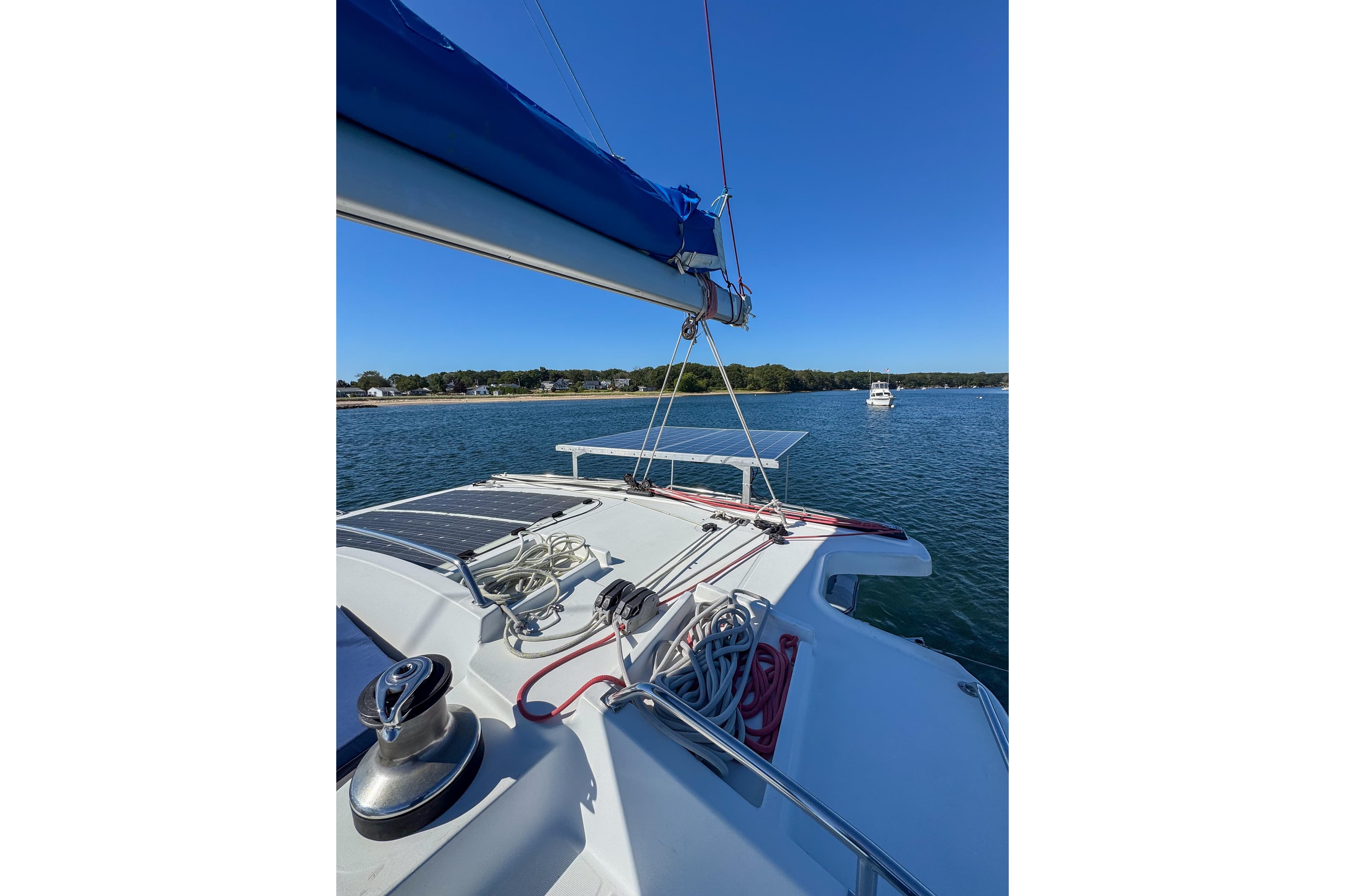 2005 Lagoon 440 catamaran on calm water with clear blue sky.