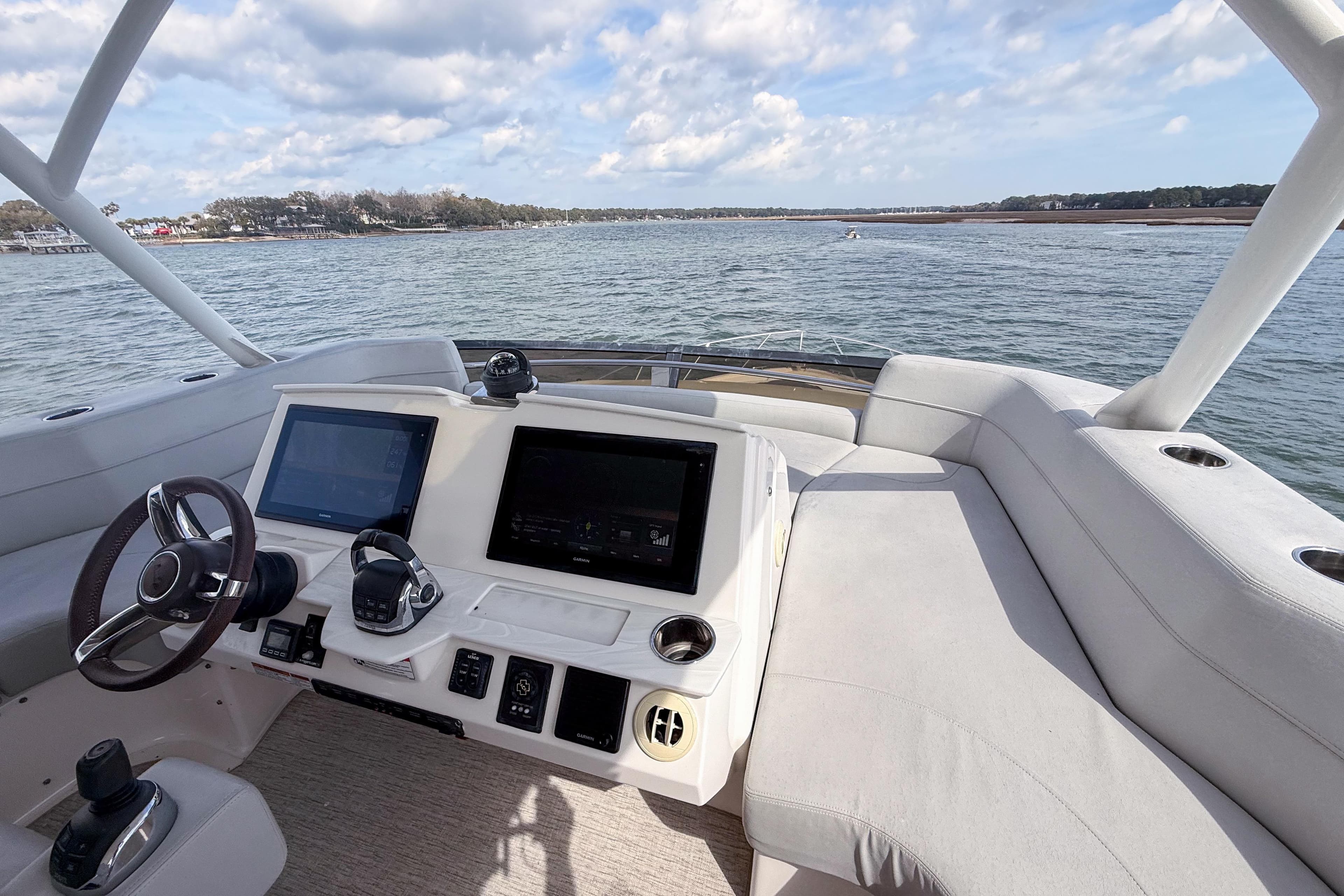 2019 Tiara Yachts F53 Flybridge helm with dual screens, steering wheel, and water view.