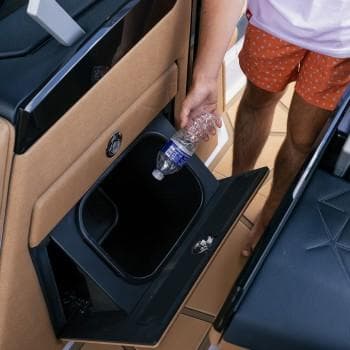 Man placing bottle in Nautique G25 Paragon MY2026 boat compartment.