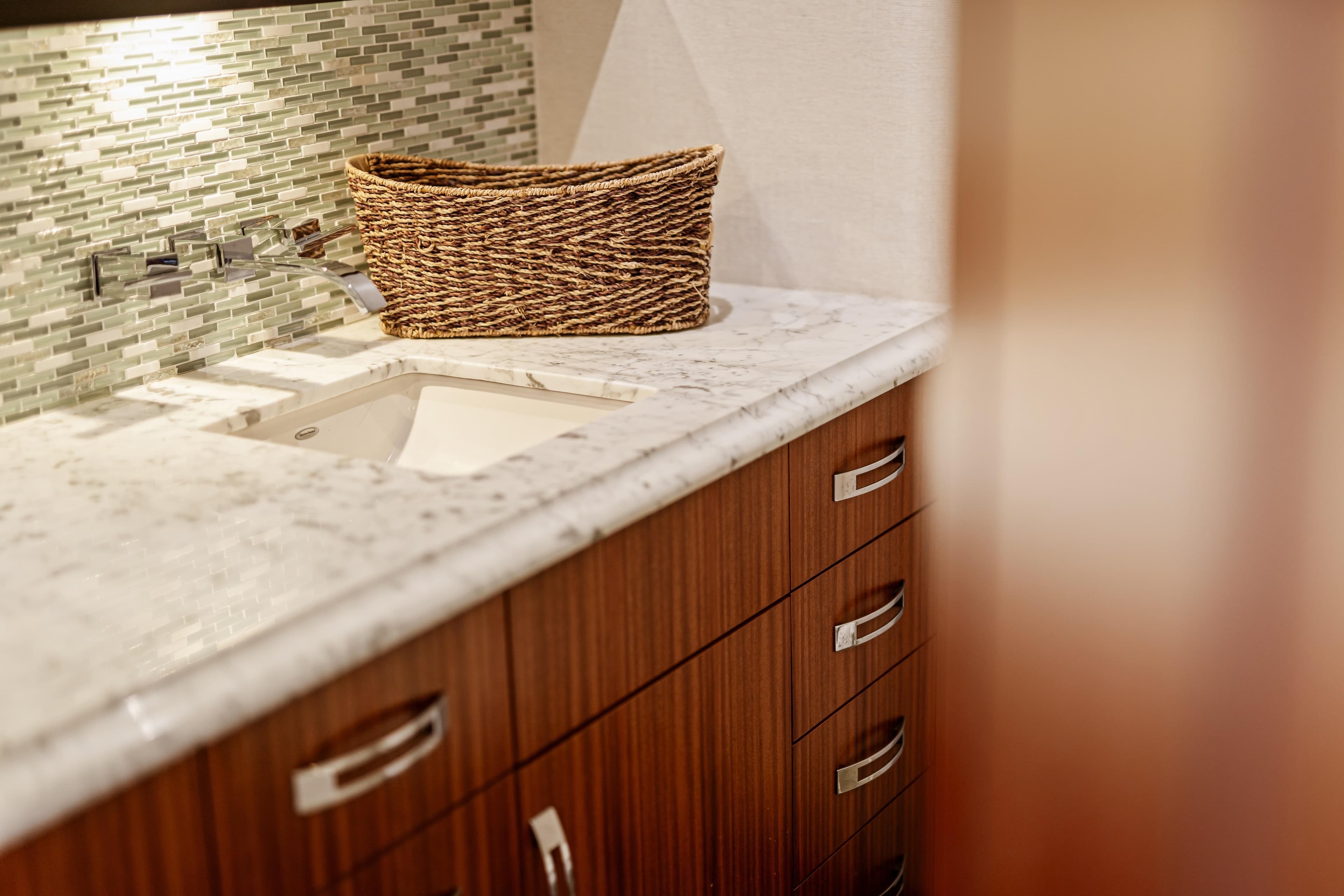 Luxurious bathroom interior of 2013 Hatteras 60 Motor Yacht with marble countertop and wicker basket.