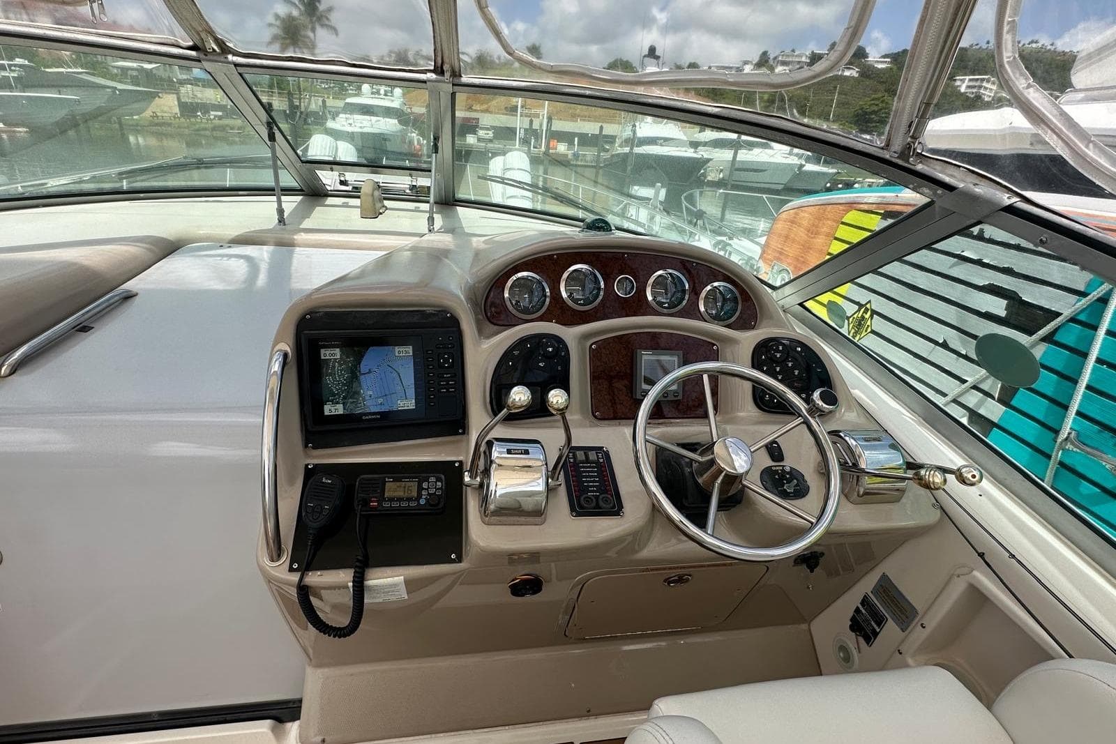 2004 Sea Ray 340 Sundancer helm with navigation equipment and steering wheel in marina setting.