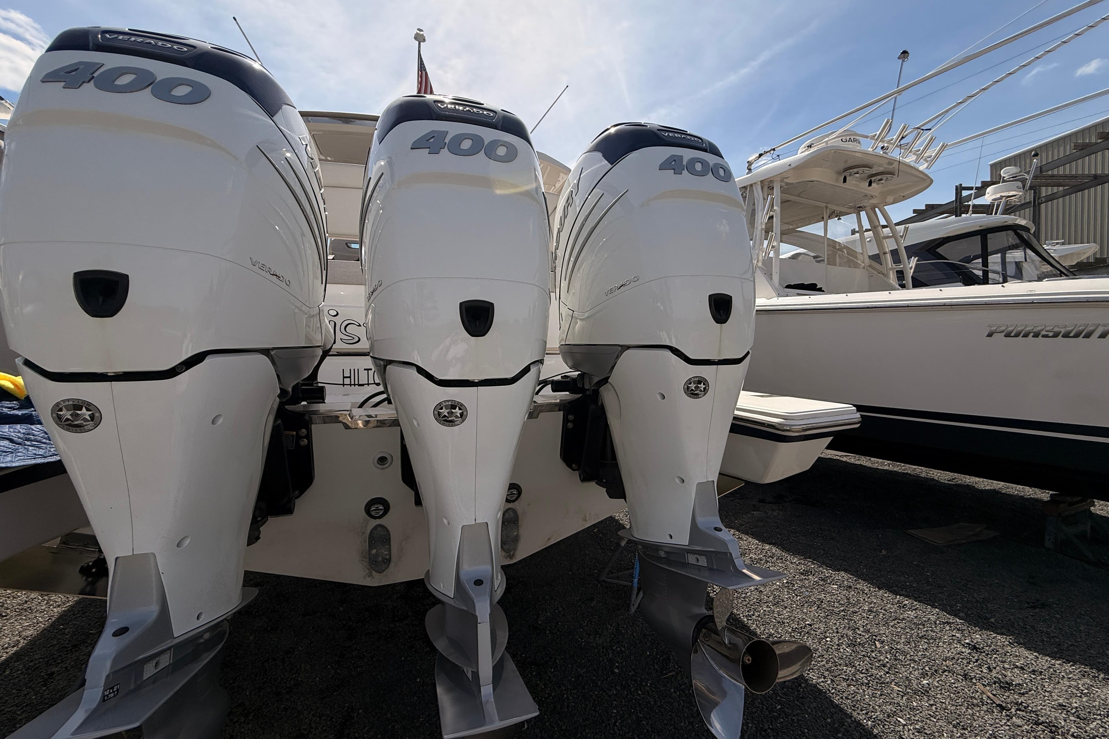 Triple outboard engines on a 2022 Tiara Yachts 38 LS, docked beside another boat.