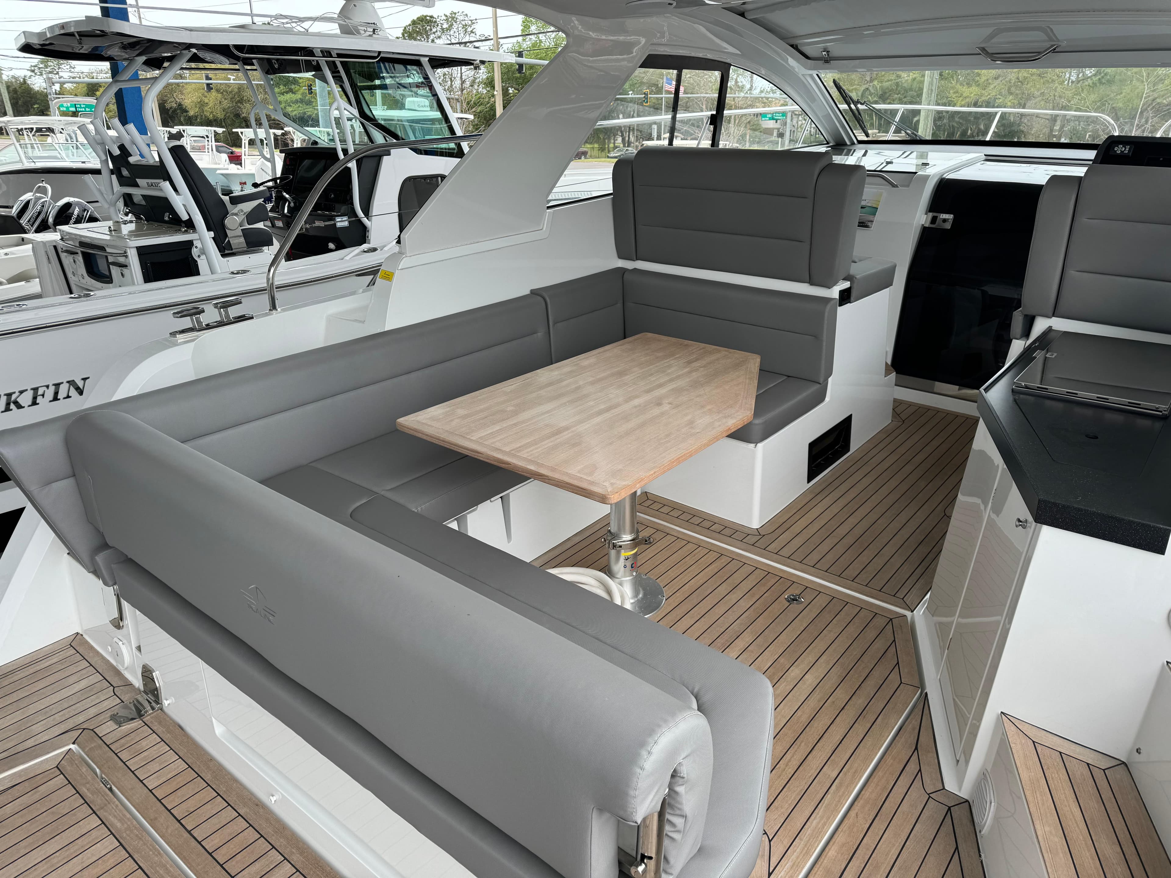 2024 Sealine S335V yacht interior with gray seating and wooden table.