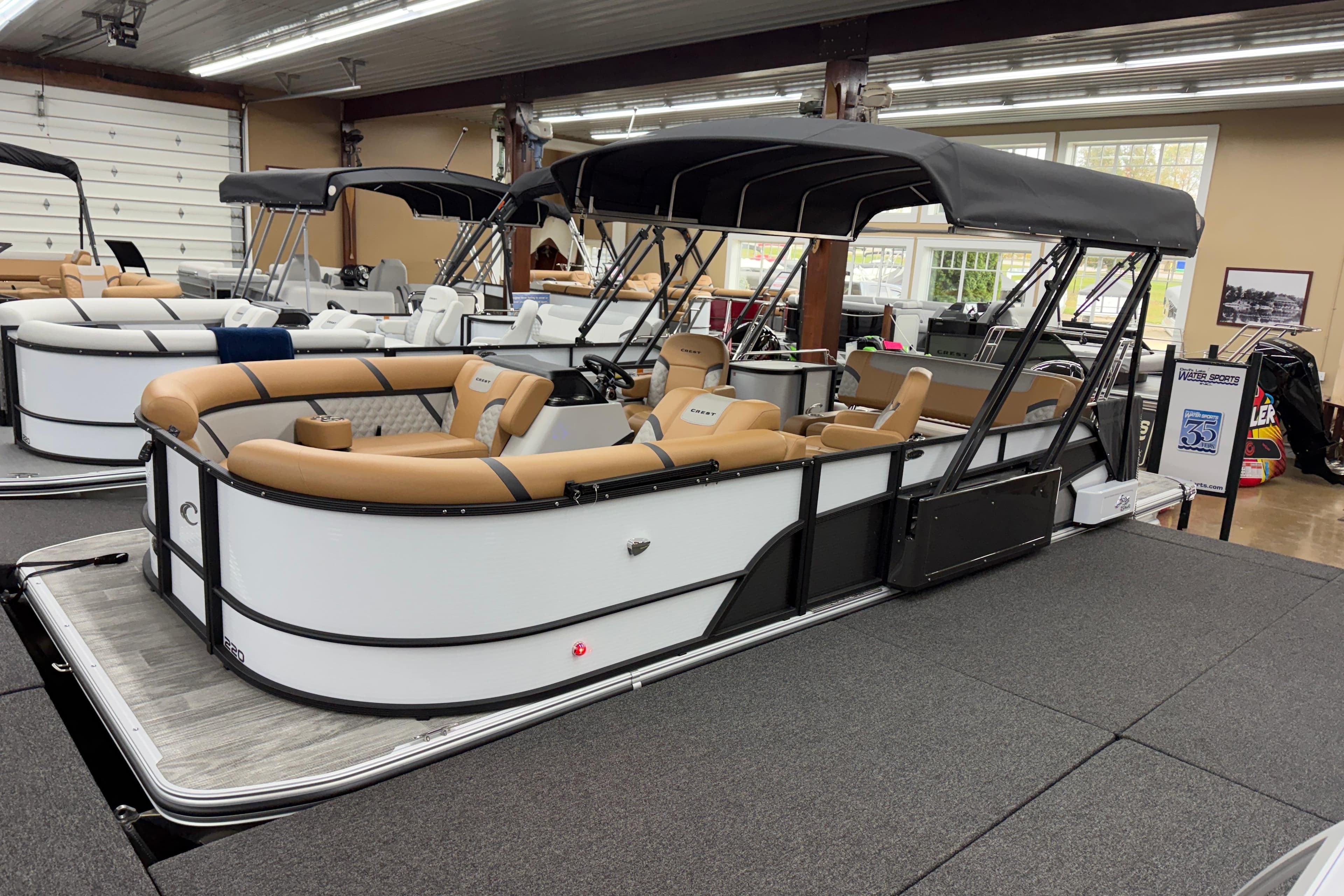 2025 Crest Classic 220 pontoon boat with tan seating and black canopy in showroom.
