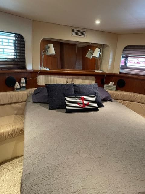 Luxurious bedroom interior of a 1996 Carver 370 yacht with cozy bedding and nautical decor.