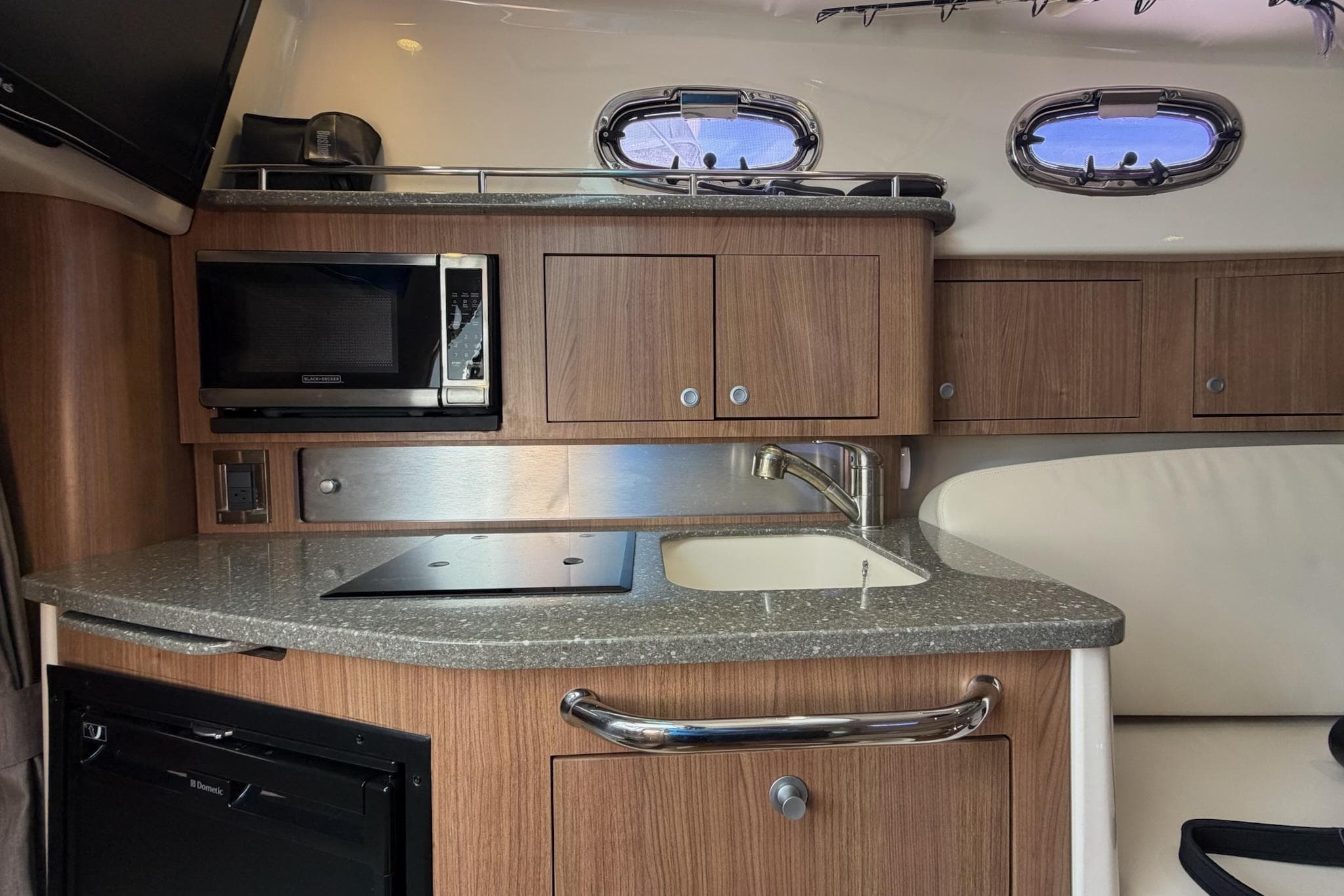 2015 Boston Whaler 315 Conquest interior kitchen with microwave, sink, and wooden cabinetry.