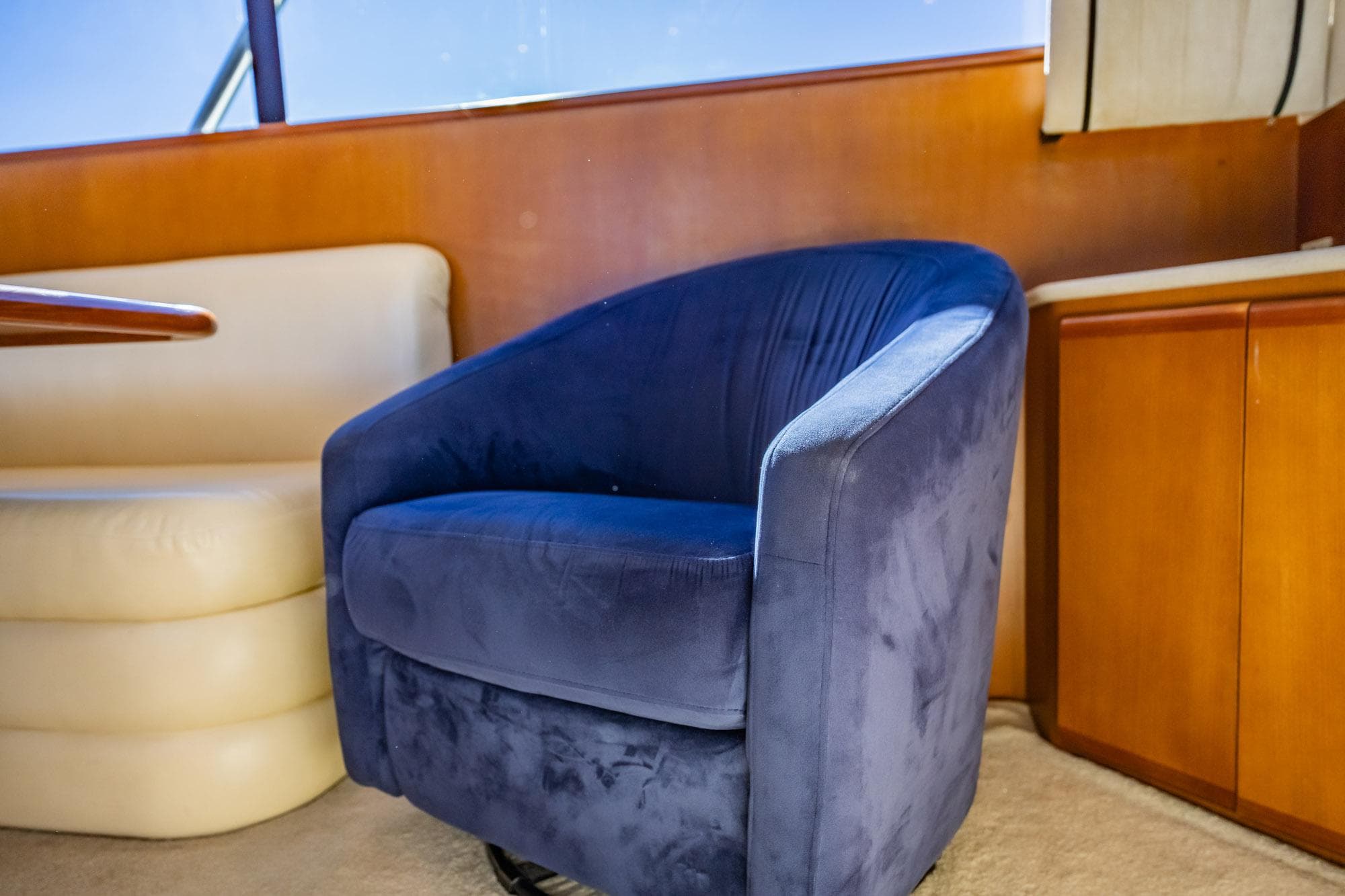 Blue swivel chair in a 2001 Post 42 yacht interior, with wooden cabinetry and cream seating.