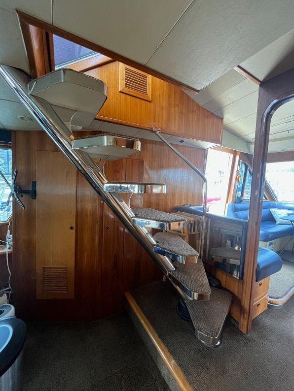Interior of 1993 Kha Shing Motoryacht with wooden stairs and seating area.