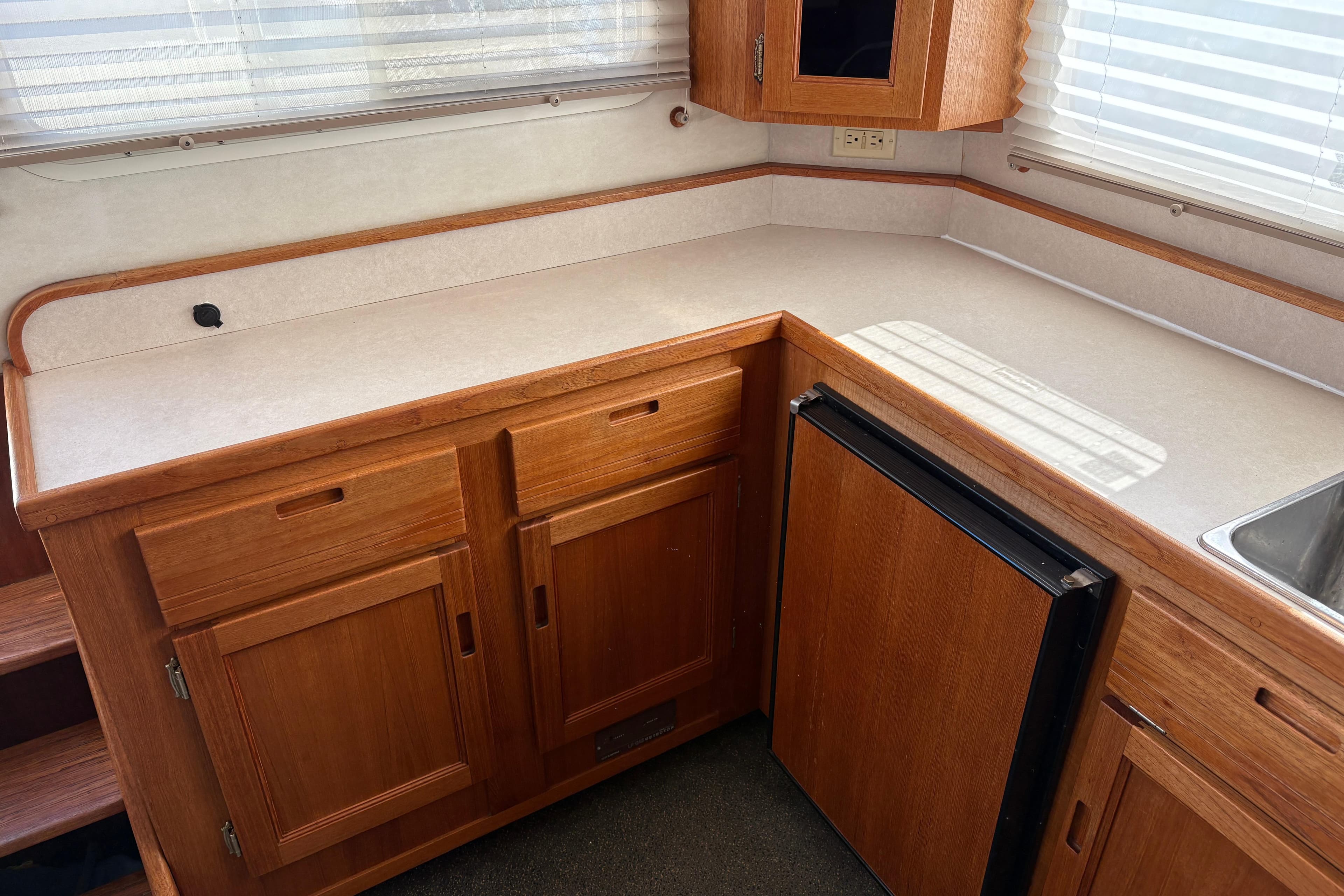 2004 Nordic Tug 32 interior kitchen with wooden cabinets and compact refrigerator.