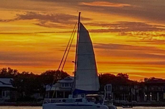 Sailboat Dolphin 460 at sunset with vibrant orange sky, 2006 model.