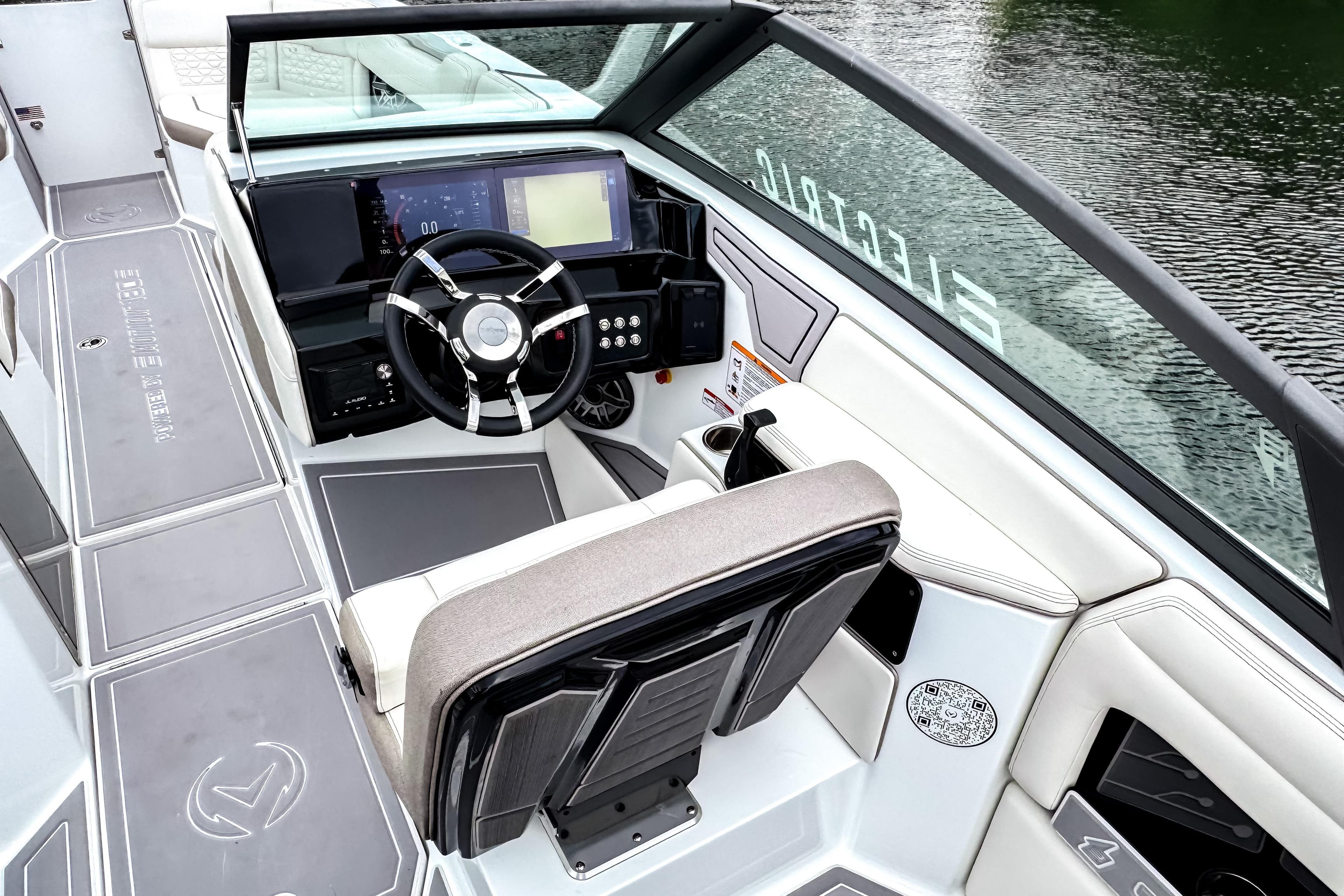 2026 Ingenity EL boat cockpit with modern steering and digital controls on a serene water backdrop.