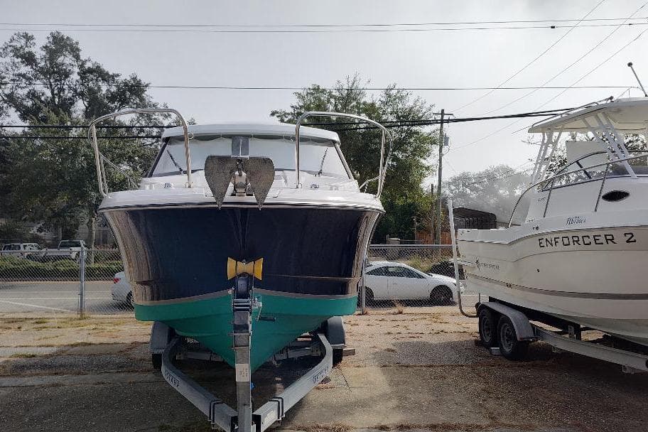 2017 Jeanneau Merry Fisher 795 boat on trailer, parked beside another boat.