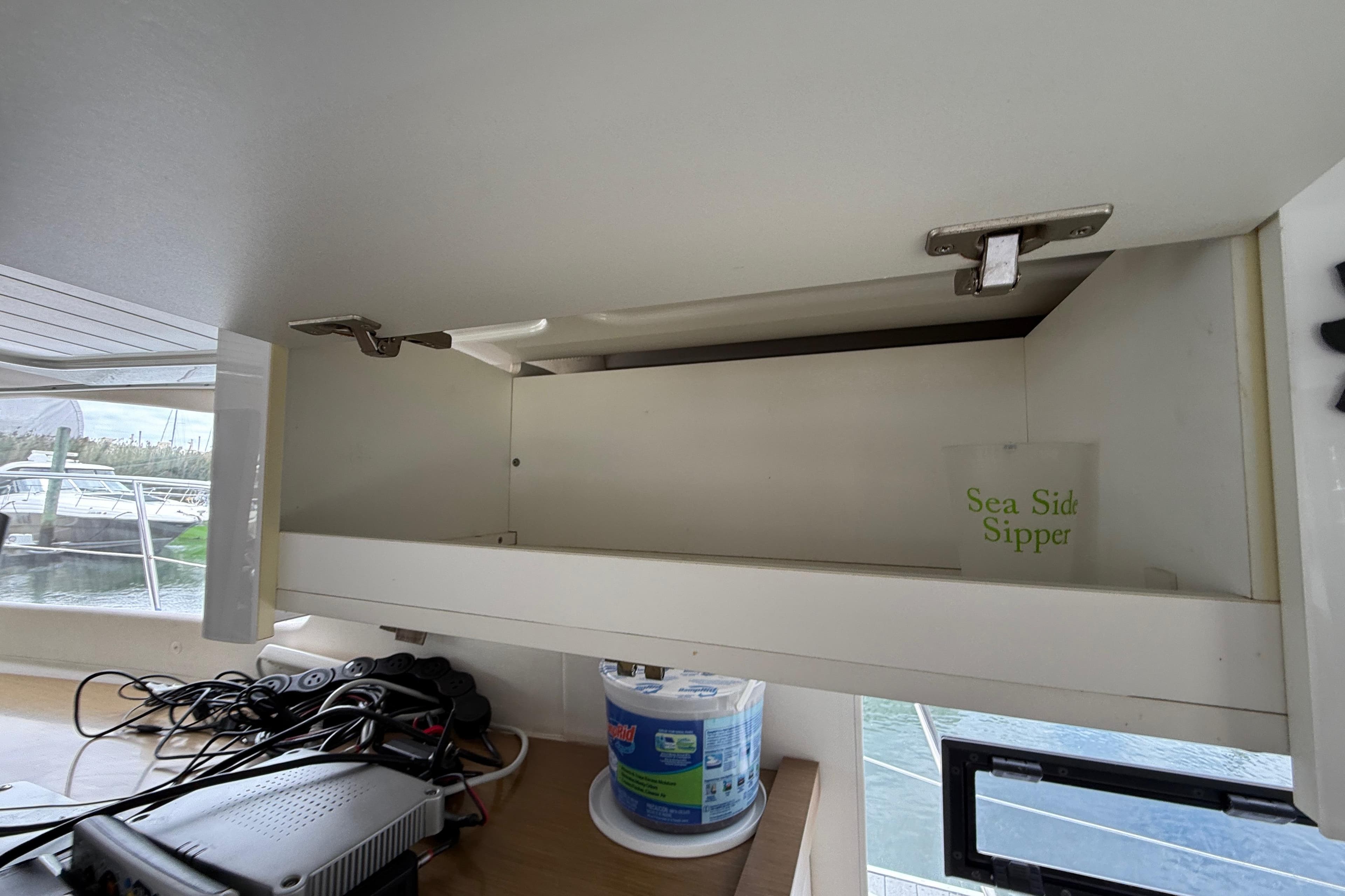 Open cabinet on 2015 Fountaine Pajot Summerland 40 LC yacht with "Sea Side Sipper" cup inside.