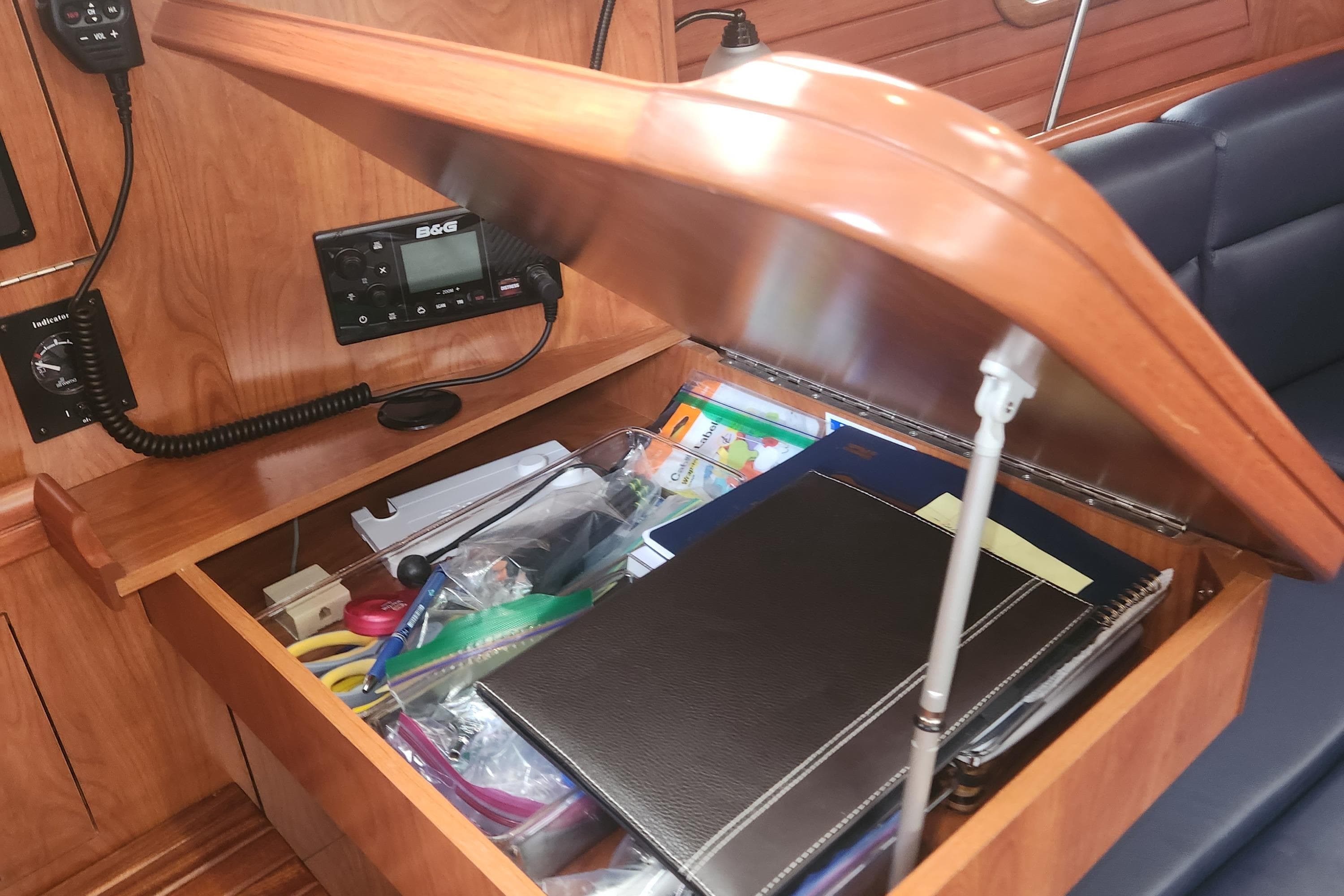 Open wooden storage compartment on 2011 Hunter 39 yacht, containing office supplies and electronics.